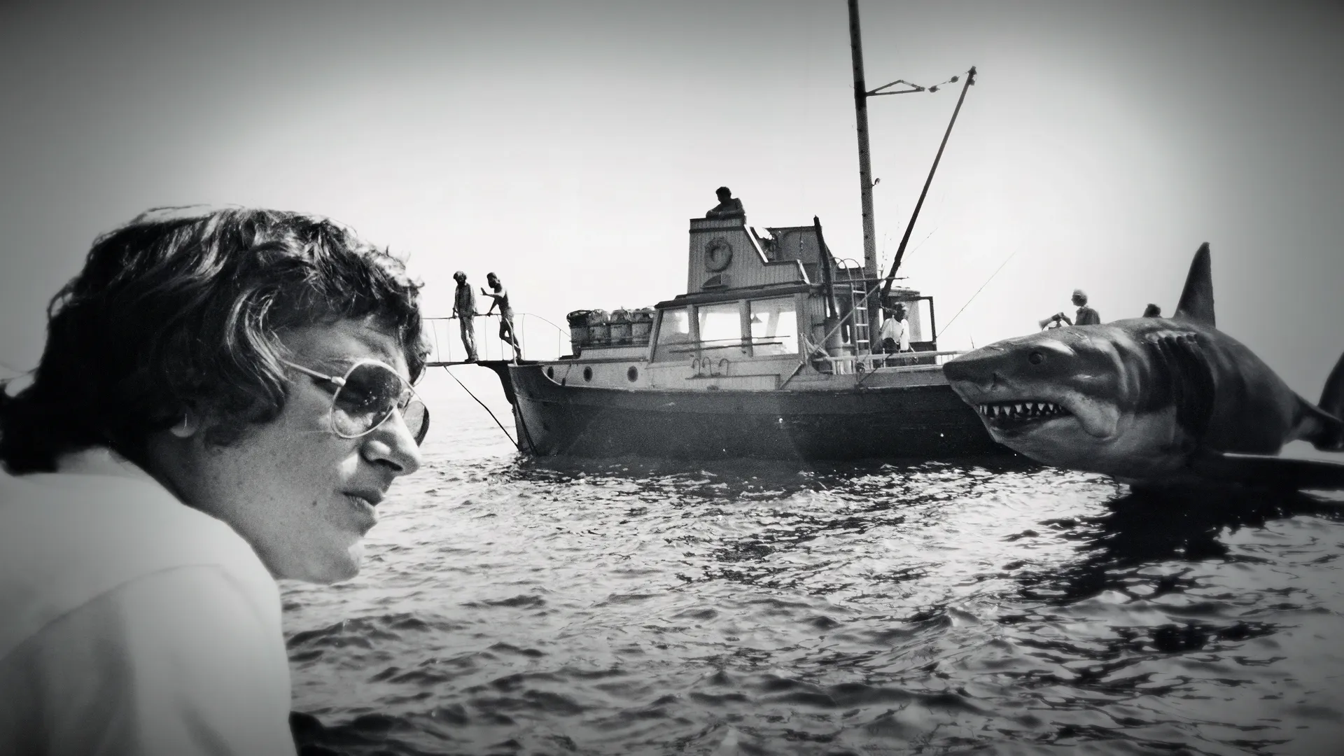Behind-the-scenes of Jaws, a young Steven Spielberg with the boat and shark props in the background.