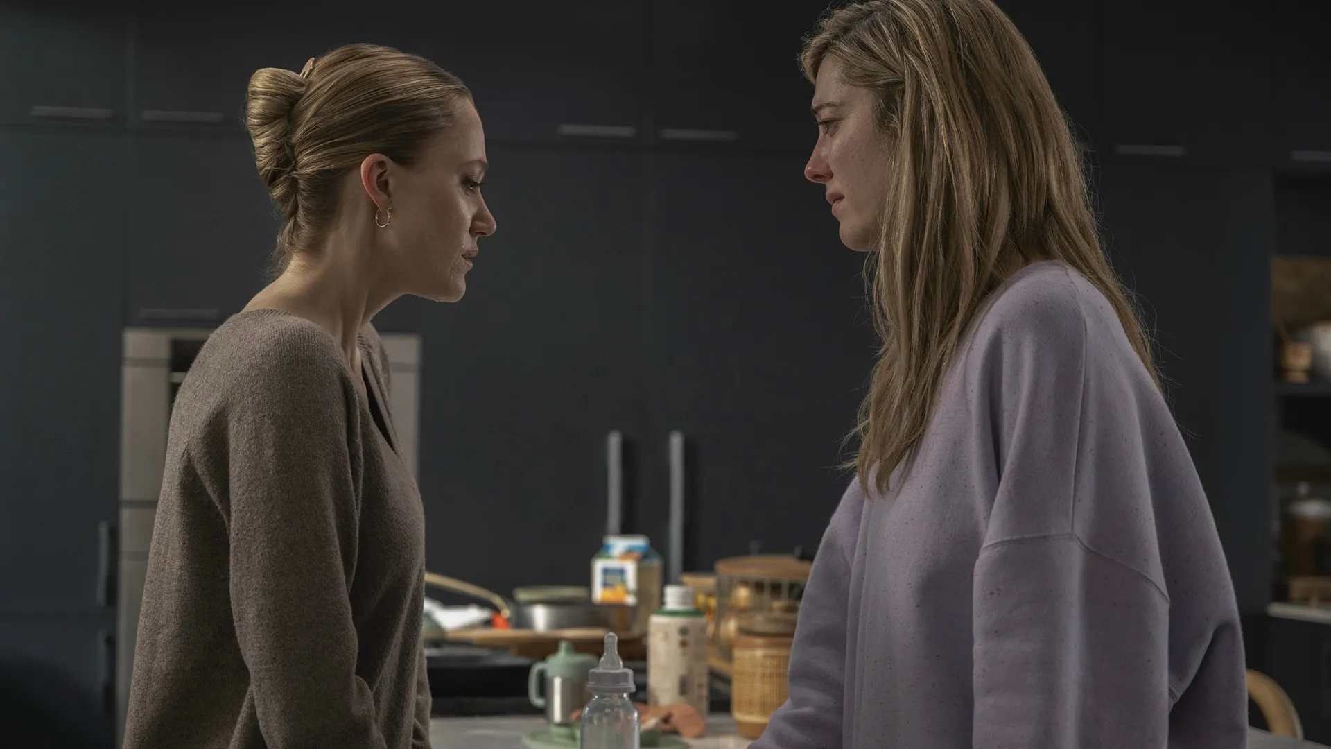 Polly Murphy (Maika Monroe) and Caitlin Morales (Mary Elizabeth Winstead) talk in a kitchen.