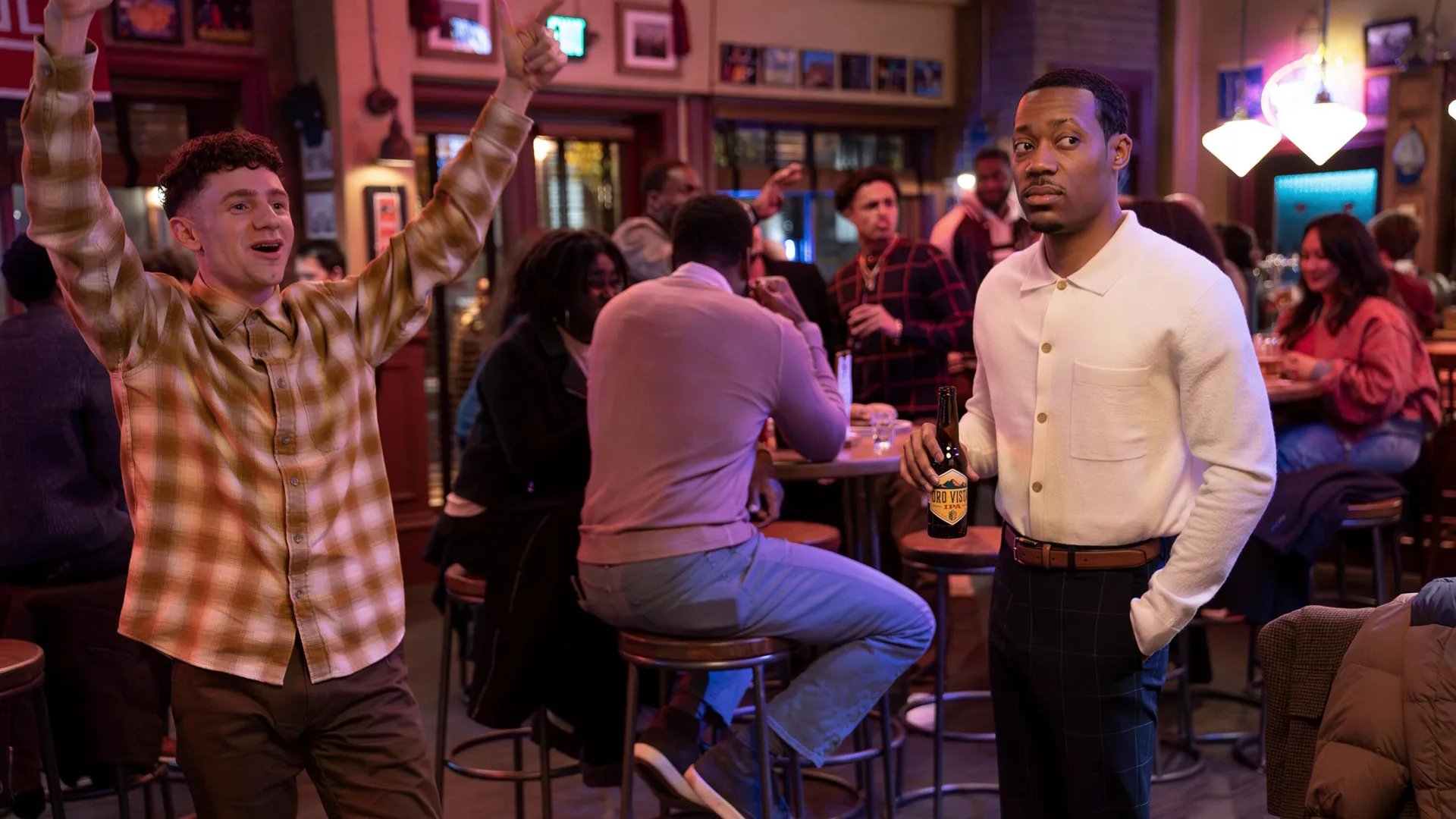 In a bar, Jacob (Chris Perfetti) cheers next to Gregory (Tyler James Williams).