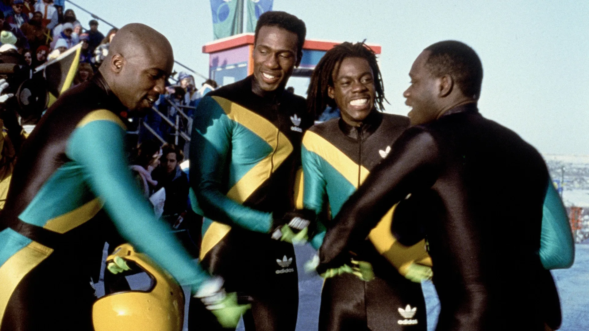Leon (Doug E. Doug), Yul (Malik Yoba), Sanka (Rawle D. Lewis) and Junior (John Candy) huddle in their racing suits sharing a moment of camaraderie.