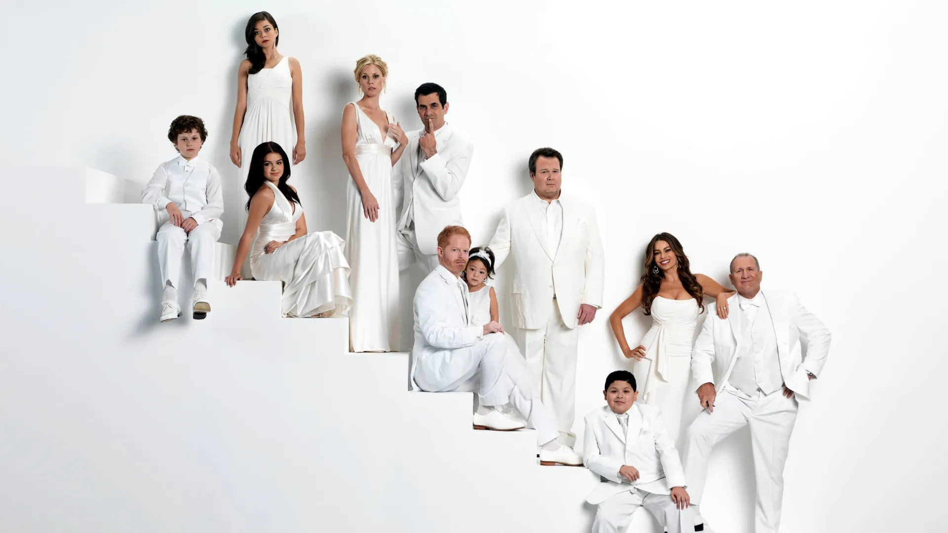 Promotional image for Modern Family showing the ensemble cast posed at different levels on a white staircase.