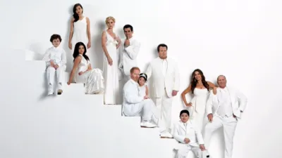 Promotional image for Modern Family showing the ensemble cast posed at different levels on a white staircase.