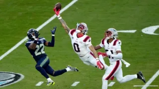 Christian Gonzalez #0 of the New England Patriots leaping with a football near the end zone.