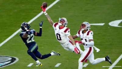 Christian Gonzalez #0 of the New England Patriots leaping with a football near the end zone.