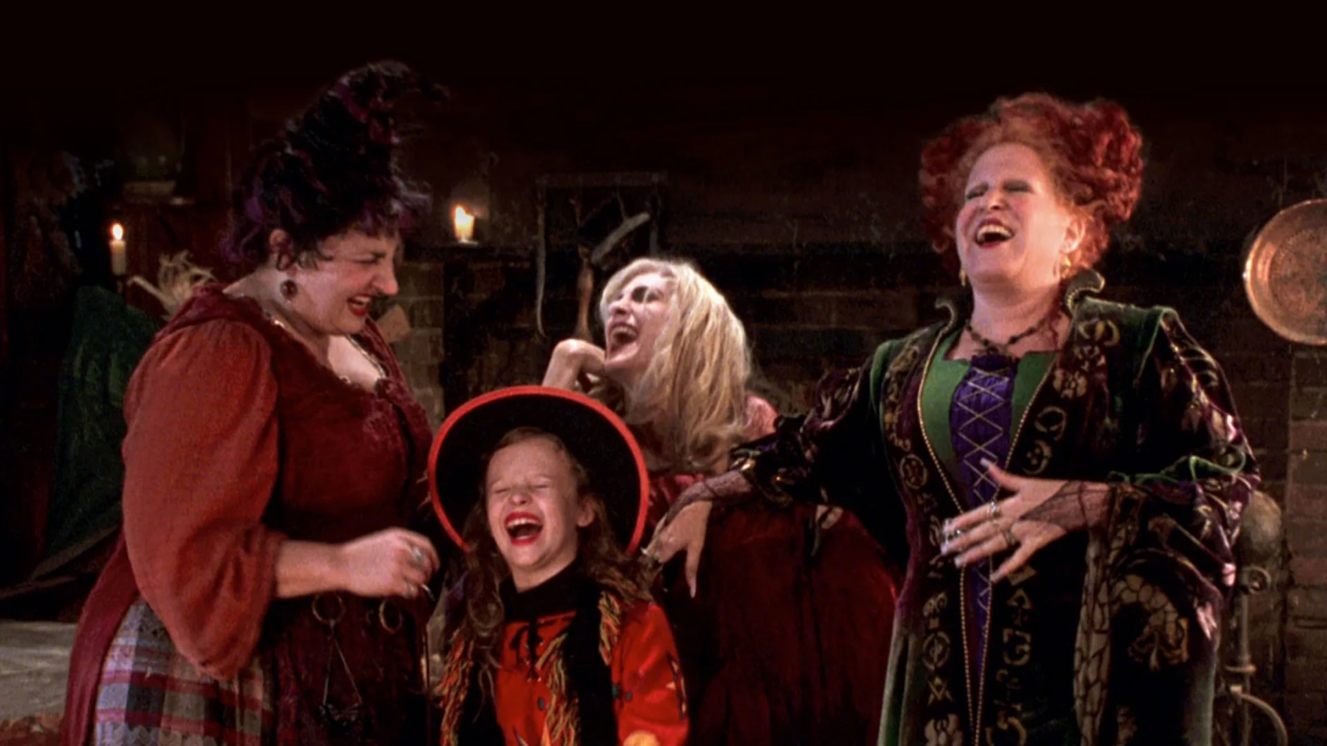 Bette Midler, Sarah Jessica Parker, Kathy Najimy, and Dani Dennison laughing in a scene of Hocus Pocus.