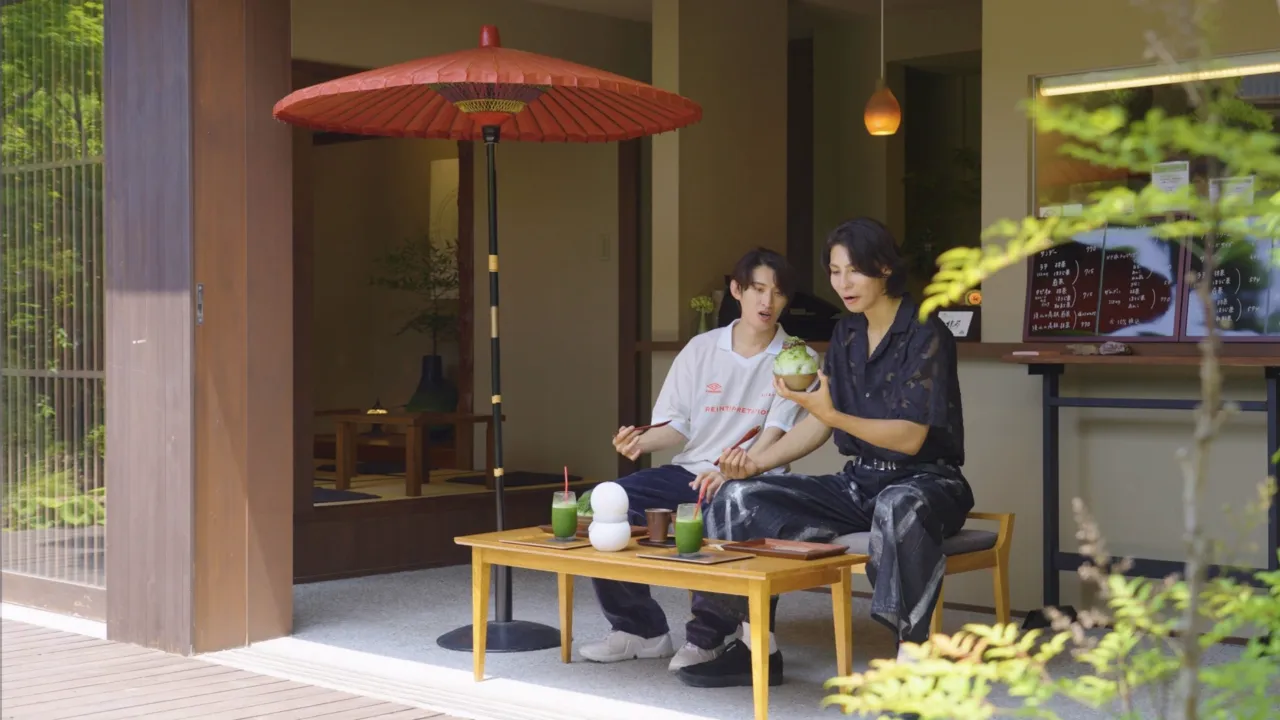 Snow Manのメンバー2人が赤い和傘の下で抹茶のかき氷を食べながら会話している様子。