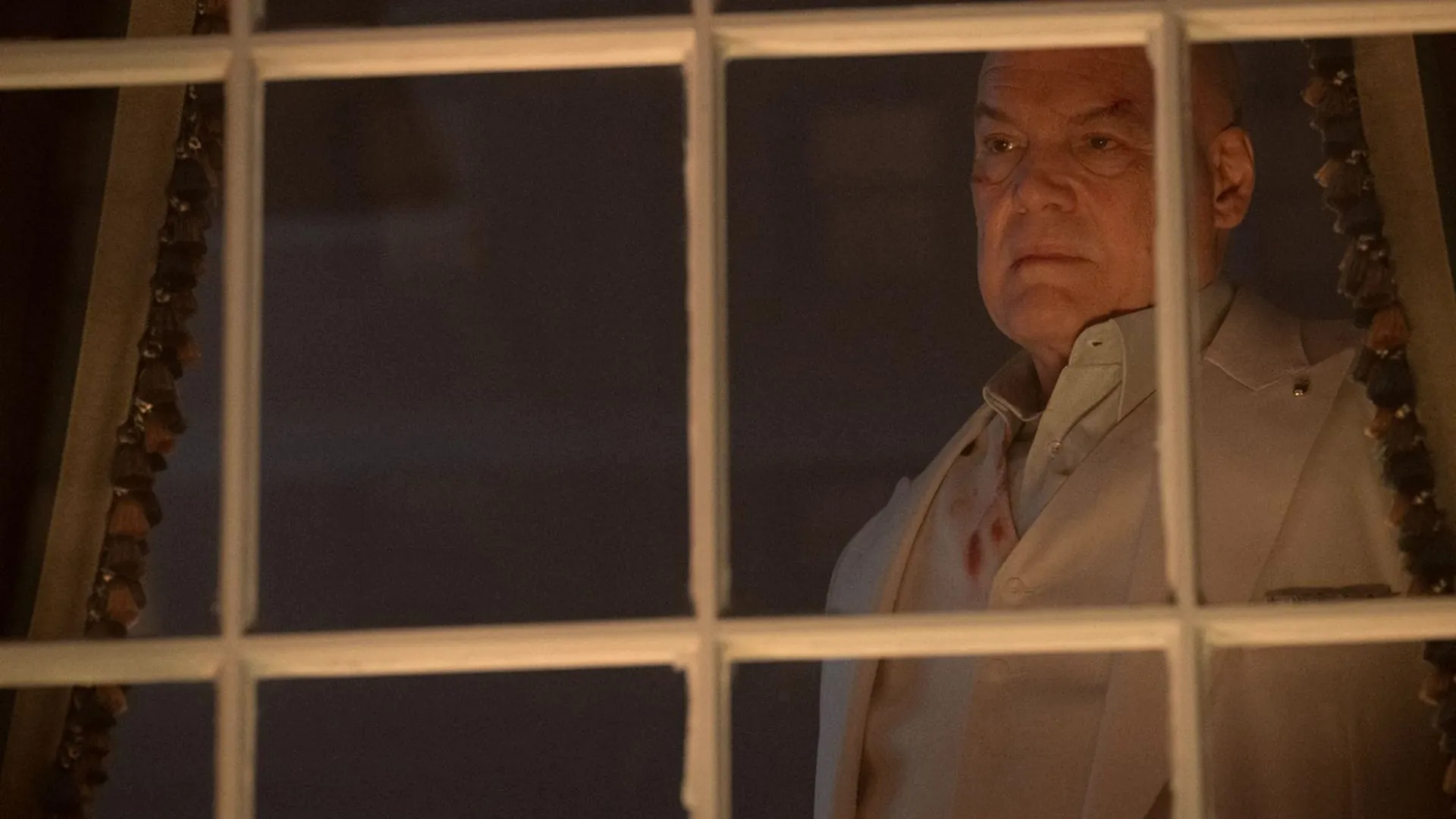 Wilson Fisk (Vincent D'Onofrio) looks out of the window as the people of New York protest his Safer Streets act.