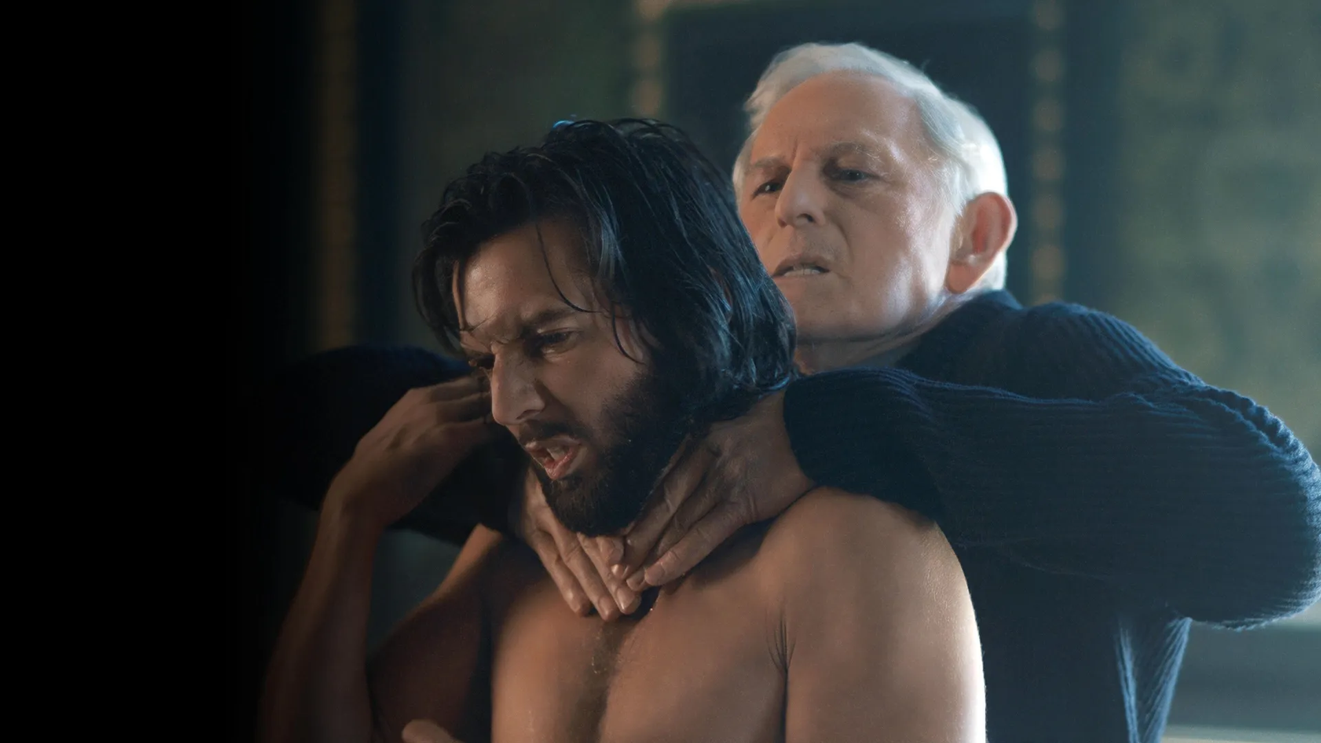 An older man strangling a younger man from behind
