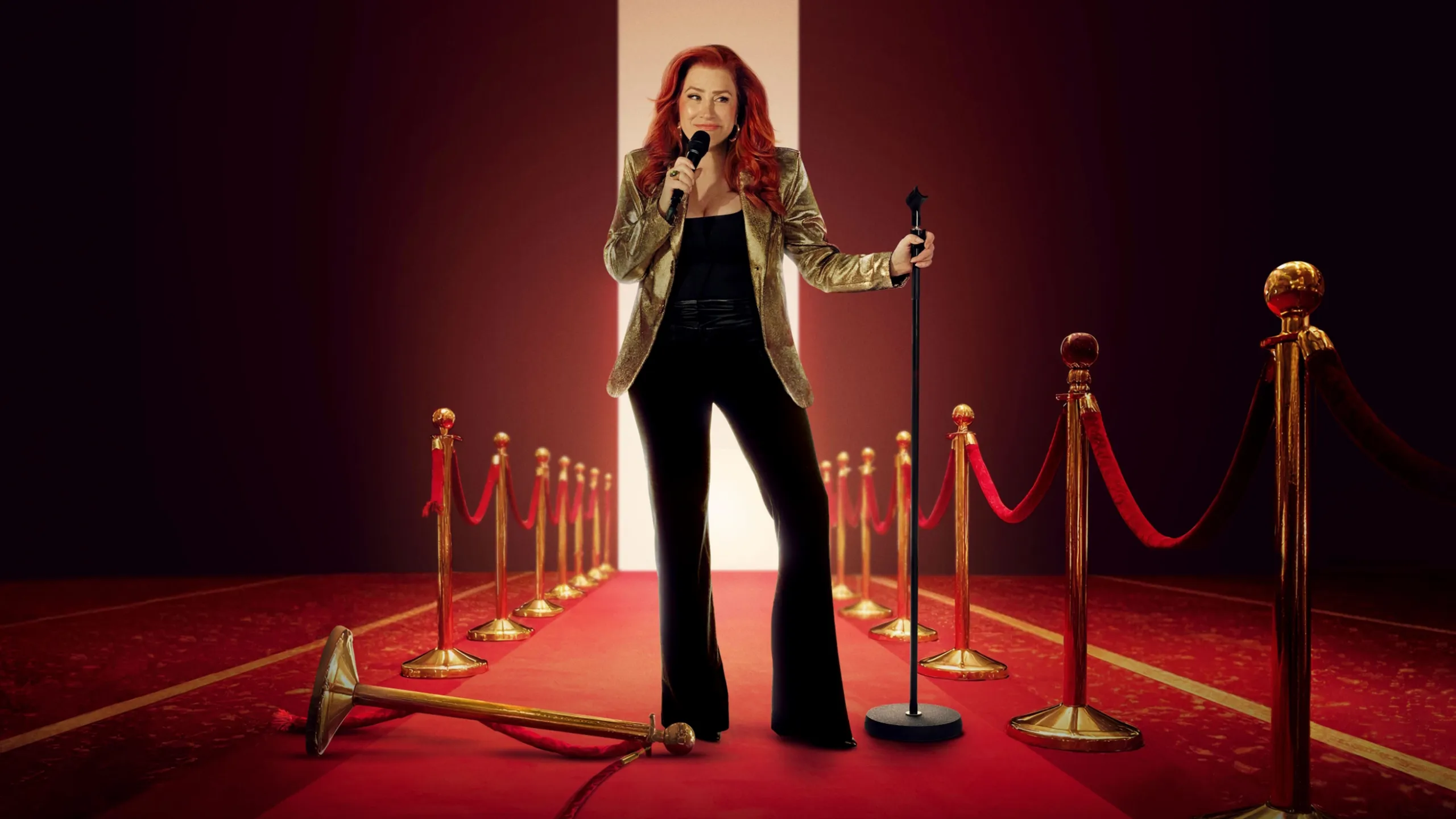 Promotional artwork for Lisa Ann Walter: It Was An Accident, featuring Lisa stood on a red carpet holding a microphone, in a black outfit and gold jacket