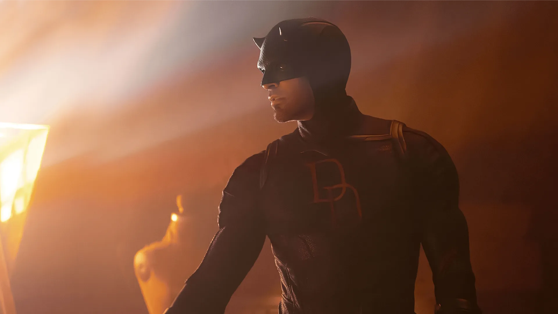 Close-up shot of Daredevil illuminated by flames in a burning building.