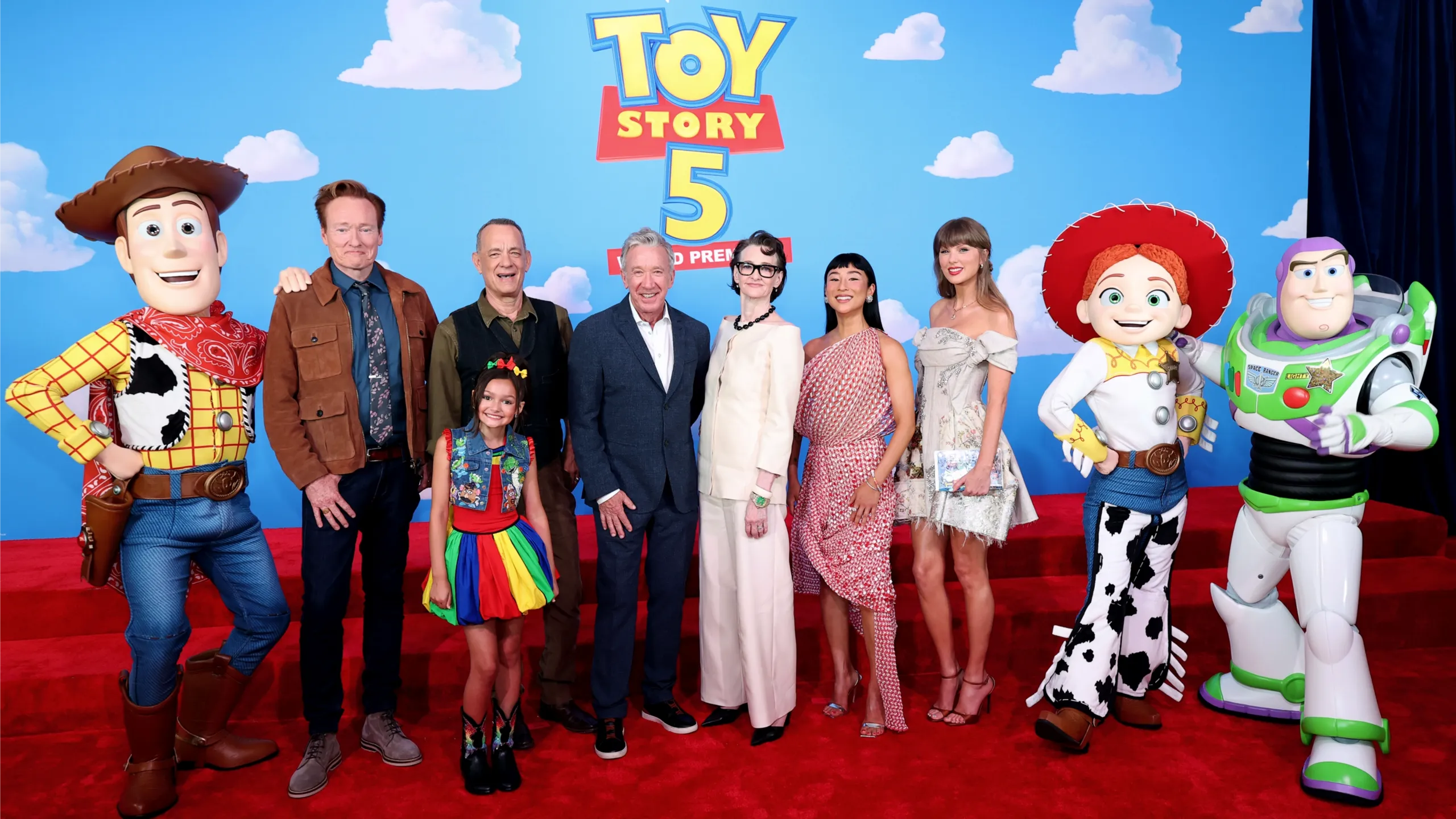 Taylor Swift junto al elenco de Toy Story 5, incluidos Tom Hanks y Tim Allen, acompañada por personajes como Woody, Buzz y Jessie, en el evento de estreno.