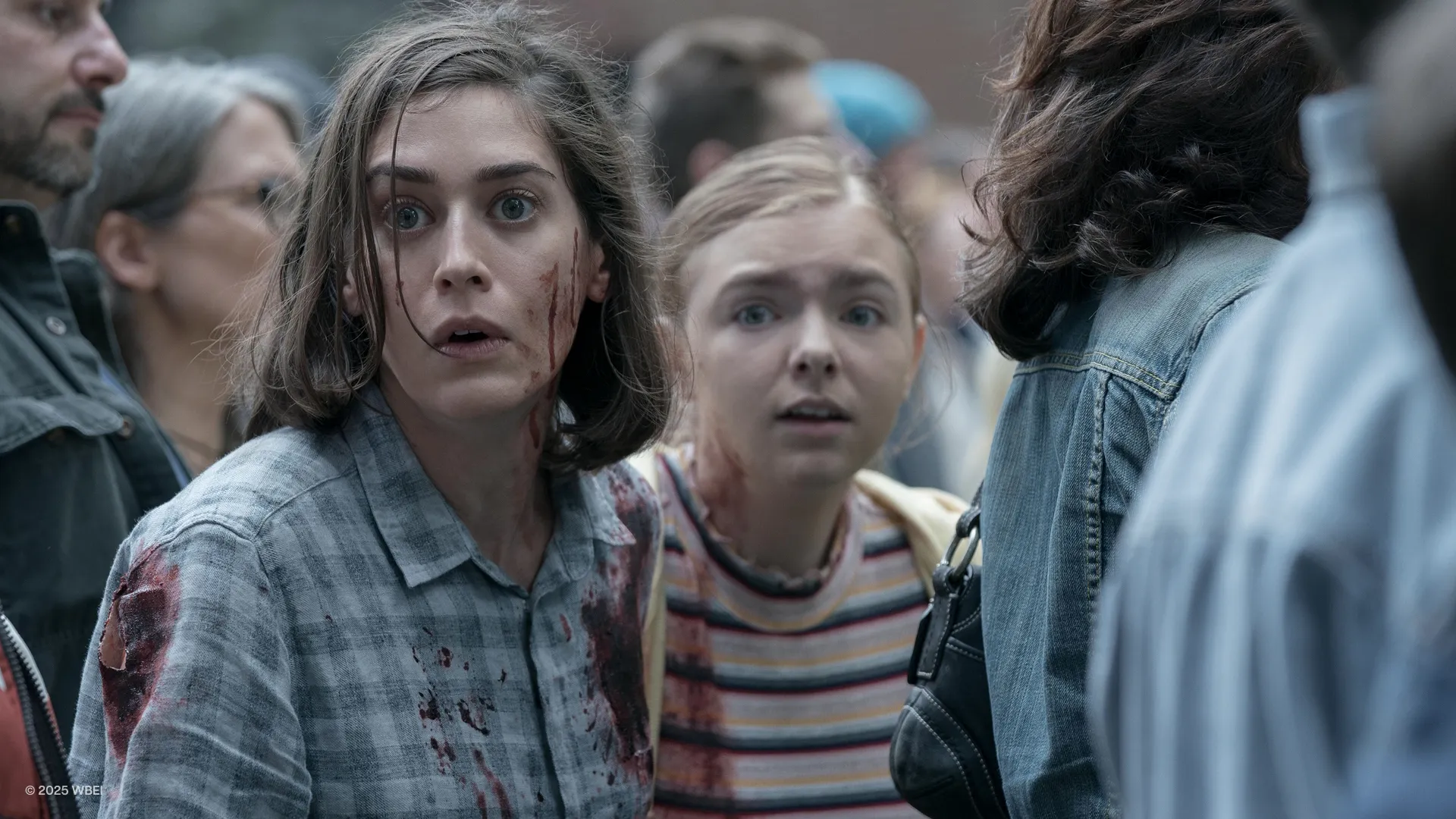 A woman and a teenage girl, both with blood on their faces and shirts 
