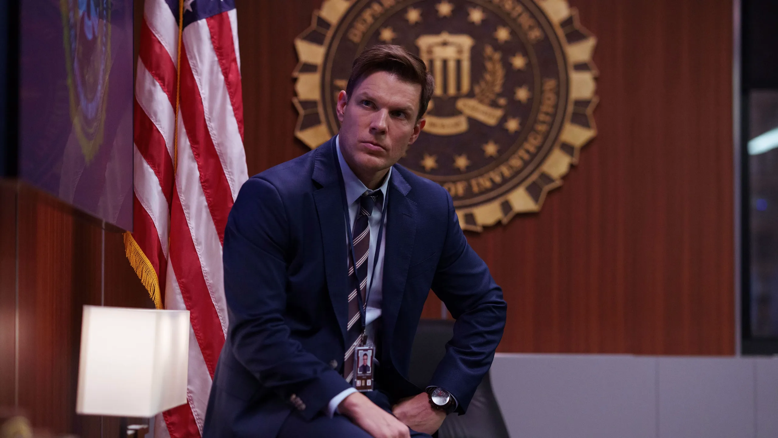 Marshall sits in an FBI office wearing a suit.