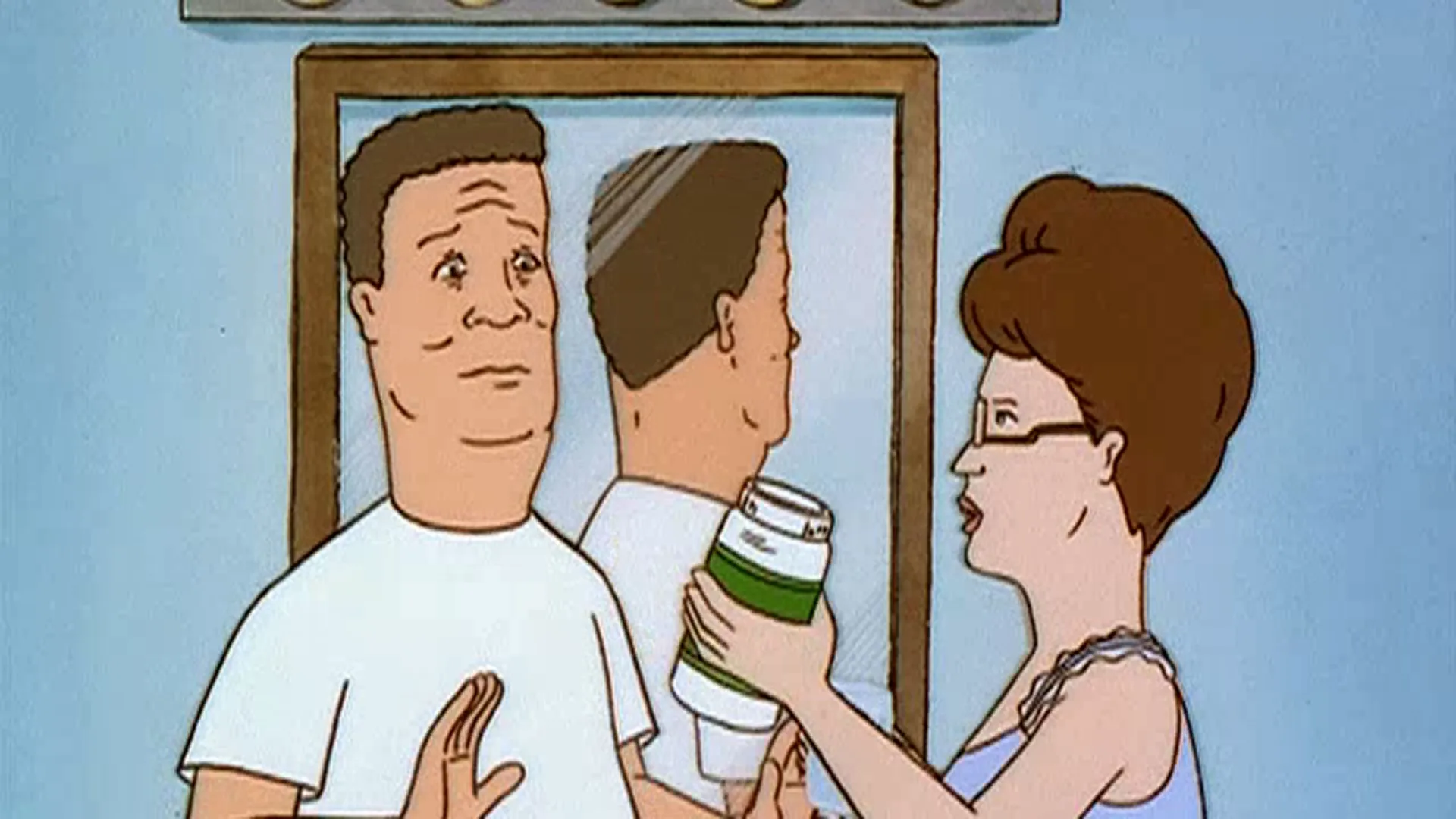 Peggy (Kathy Najimy) holds up a large pill bottle beside a wary Hank (Mike Judge) in their bathroom.