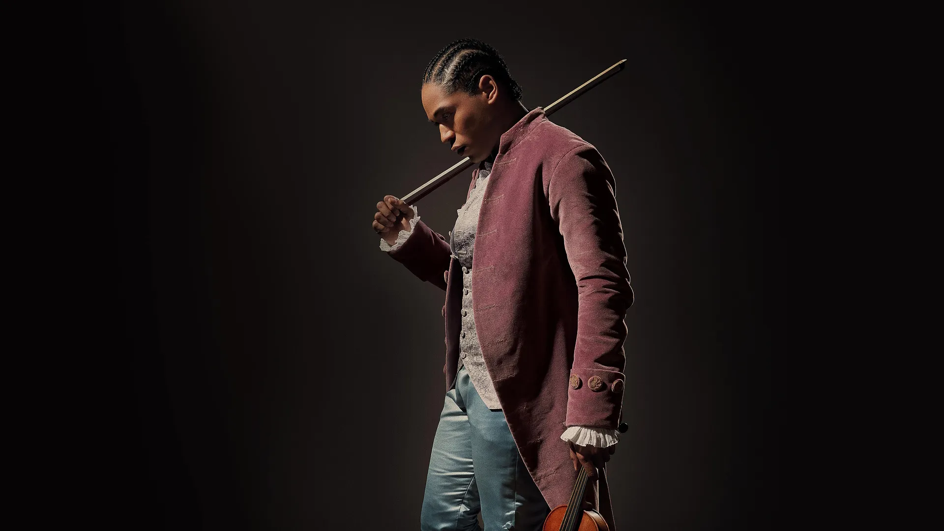 Kelvin Harrison Jr. as Joseph Bologne, Chevalier de Saint-Georges wearing 18th century clothing holding a violin bow.