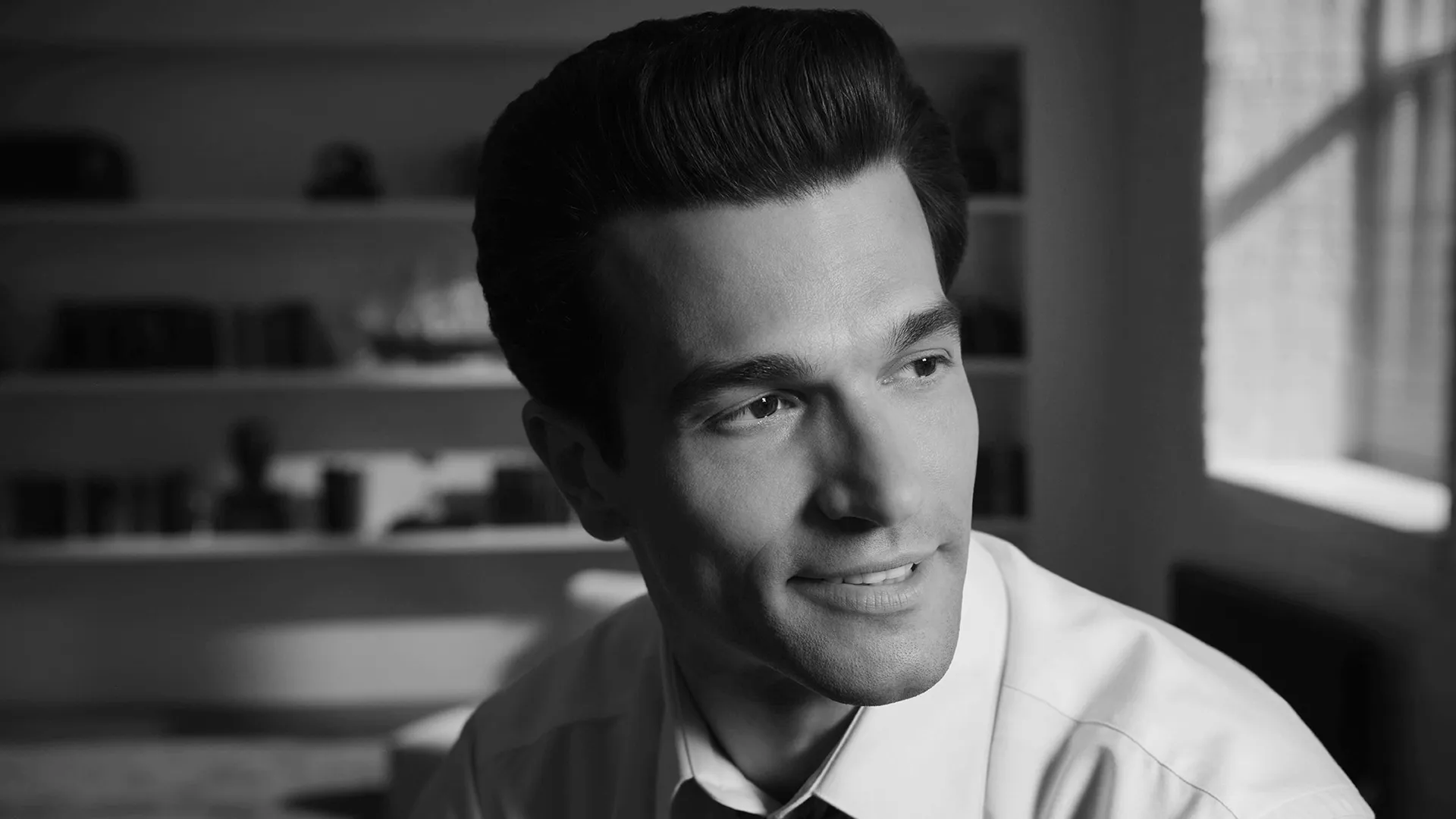 Close-up shot of John F. Kennedy Jr. (Paul Kelly) in a black and white set photo from FX's Love Story.