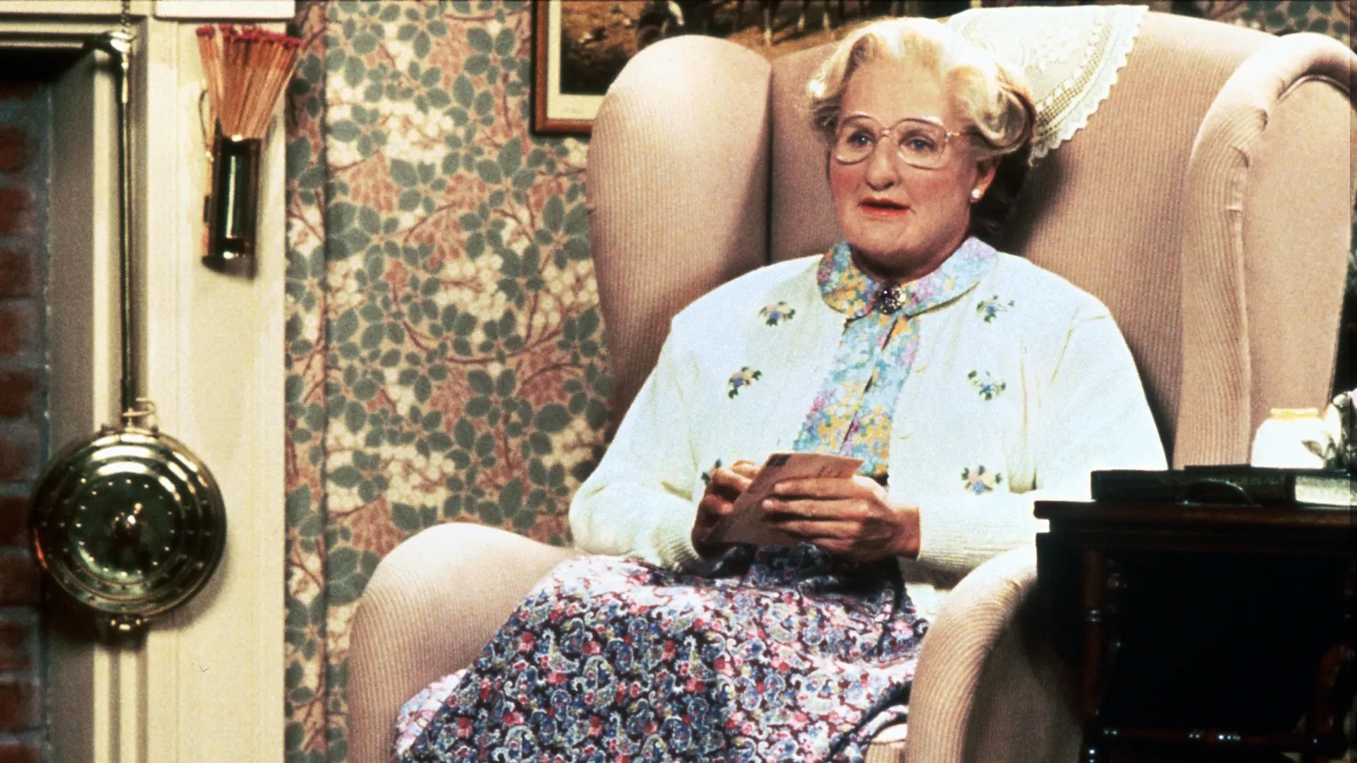 Mrs Doubtfire (Robin Williams) sitting down.