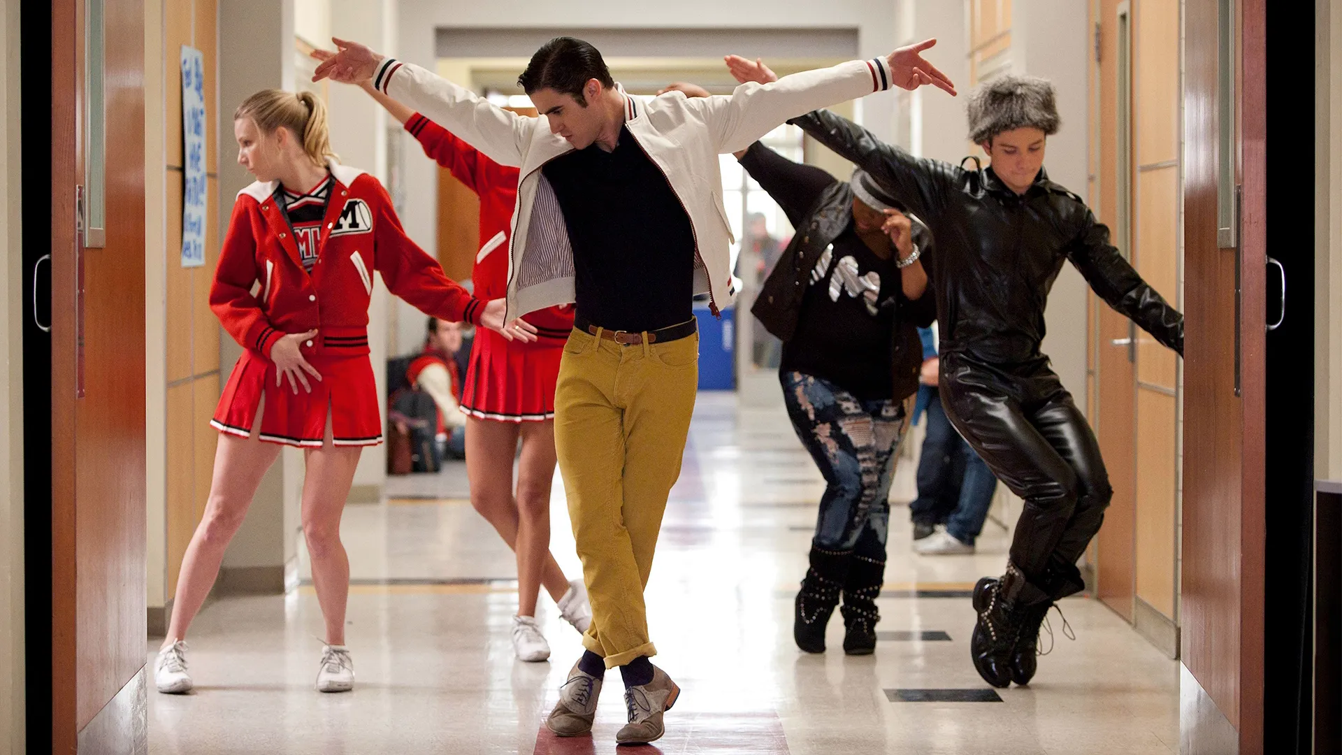 Cast of Glee dancing in the hallway of the school.