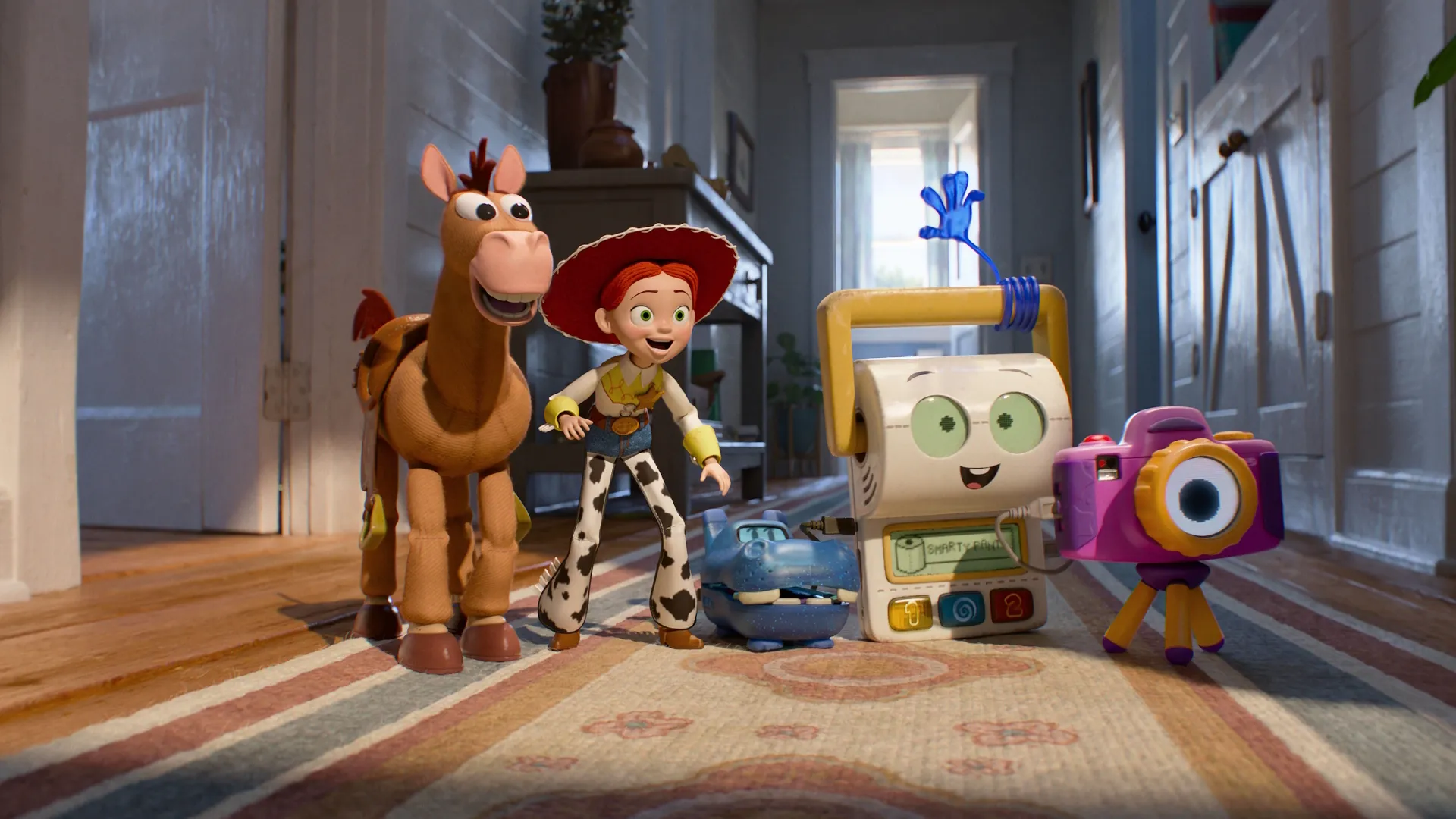 Bullseye and Jessie the cowgirl standing on a hallway rug alongside new tech toys Atlas the blue hippo, Smarty Pants the white toilet-training device, and Snappy the purple camera from Disney and Pixar's Toy Story 5.