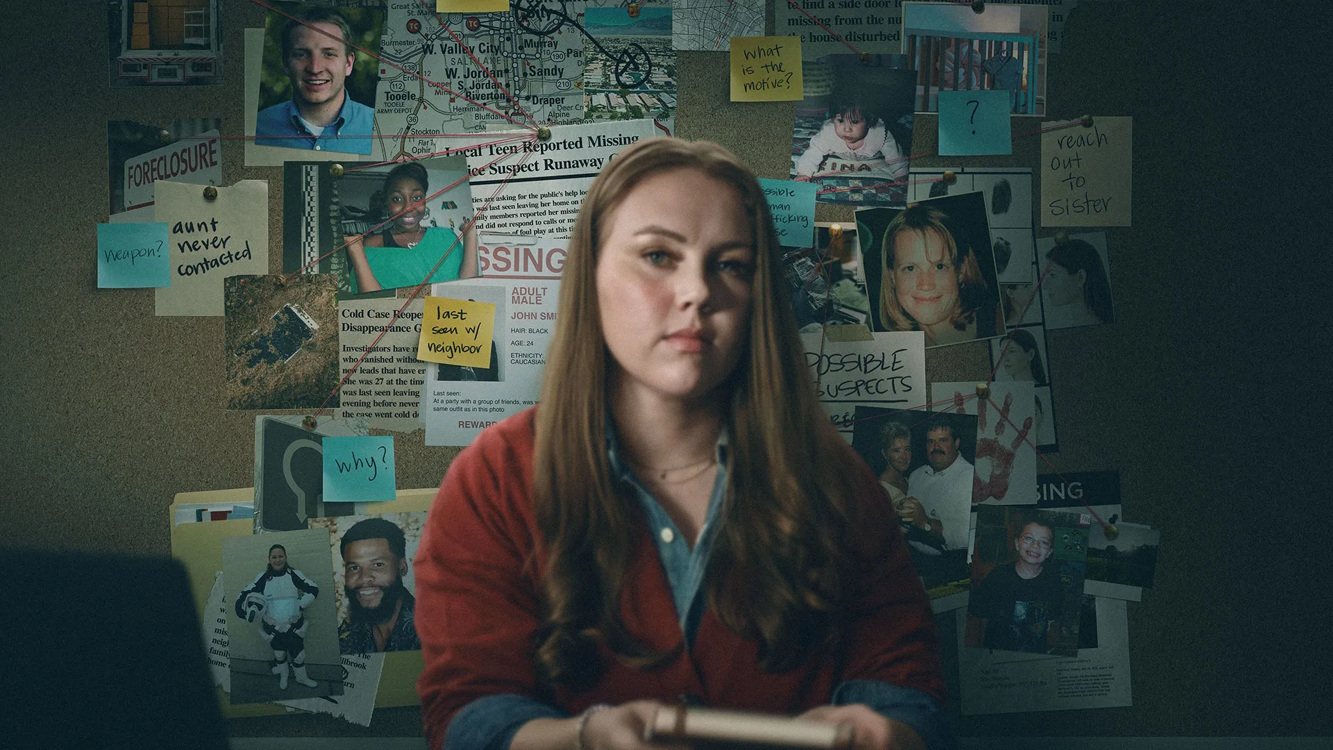 A person sits in front of an investigation board covered with photographs, newspaper clippings, maps and handwritten notes.