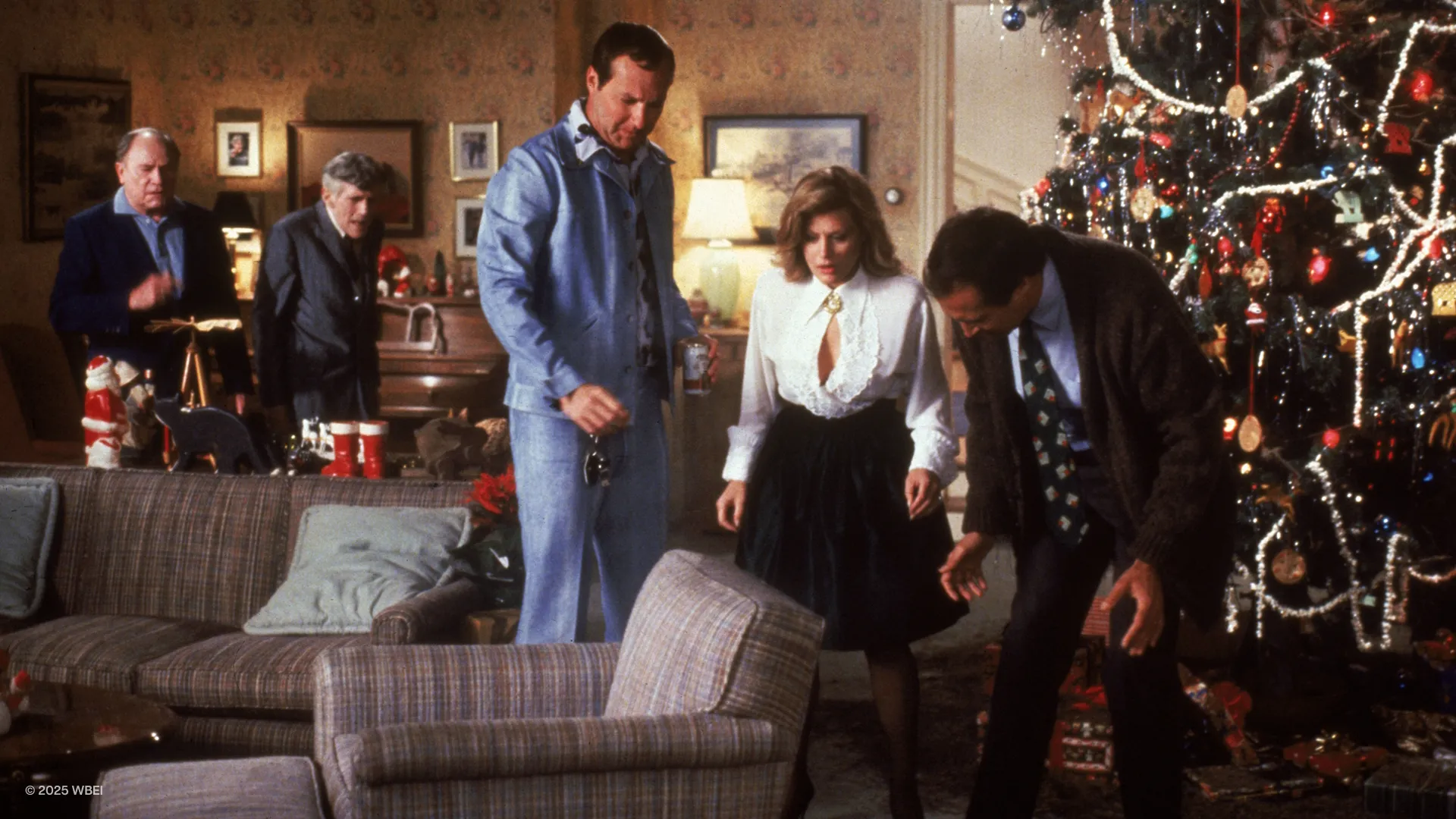 Cousin Eddie (Randy Quaid), Ellen Griswold (Beverly D'Angelo), and Clark Griswold (Chevy Chase) look in worry and disgust at the floor of the Griswolds' living room.