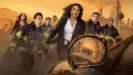 9-1-1 Season 10 promotional art featuring the main cast lead by Athena Grant (Angela Bassey) facing an erupting volcano reflected in a car's melting wing mirror.