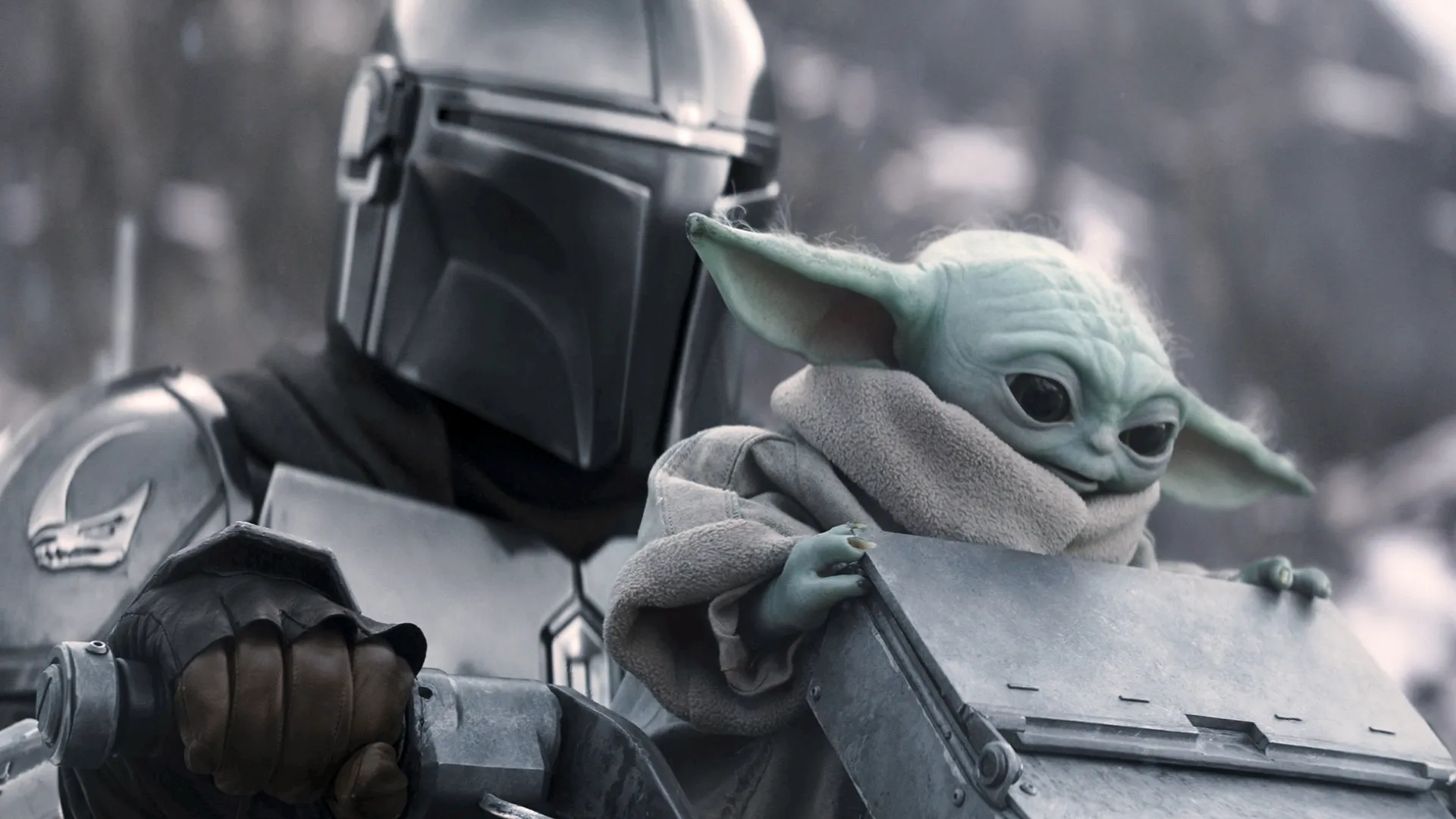 The image shows the armored bounty hunter Din Djarin (the Mandalorian) riding a speeder bike with his green, large-eared companion Grogu (affectionately known by fans as Baby Yoda) from the Star Wars: The Mandalorian and Grogu film.