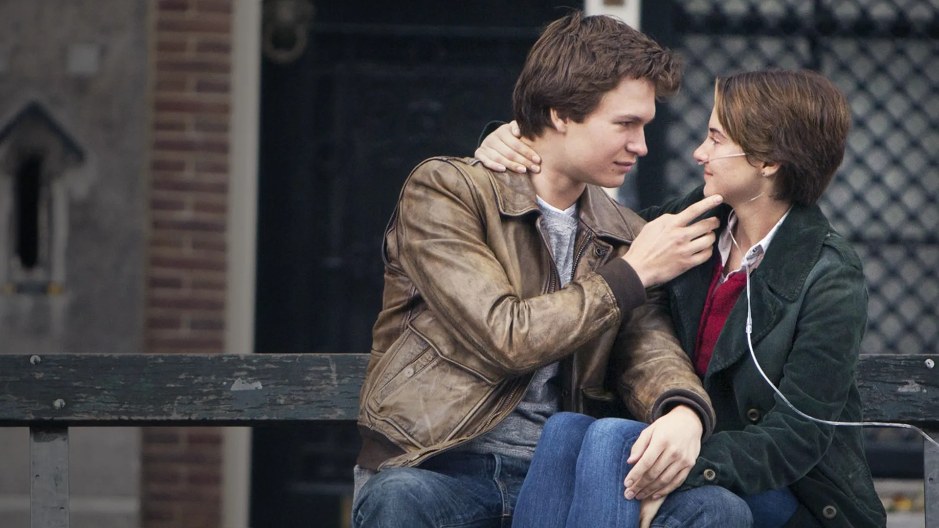 On a bench outside, Augustus (Ansel Elgort) touches Hazel's (Shailene Woodley) face, who is wearing a nasal cannula
