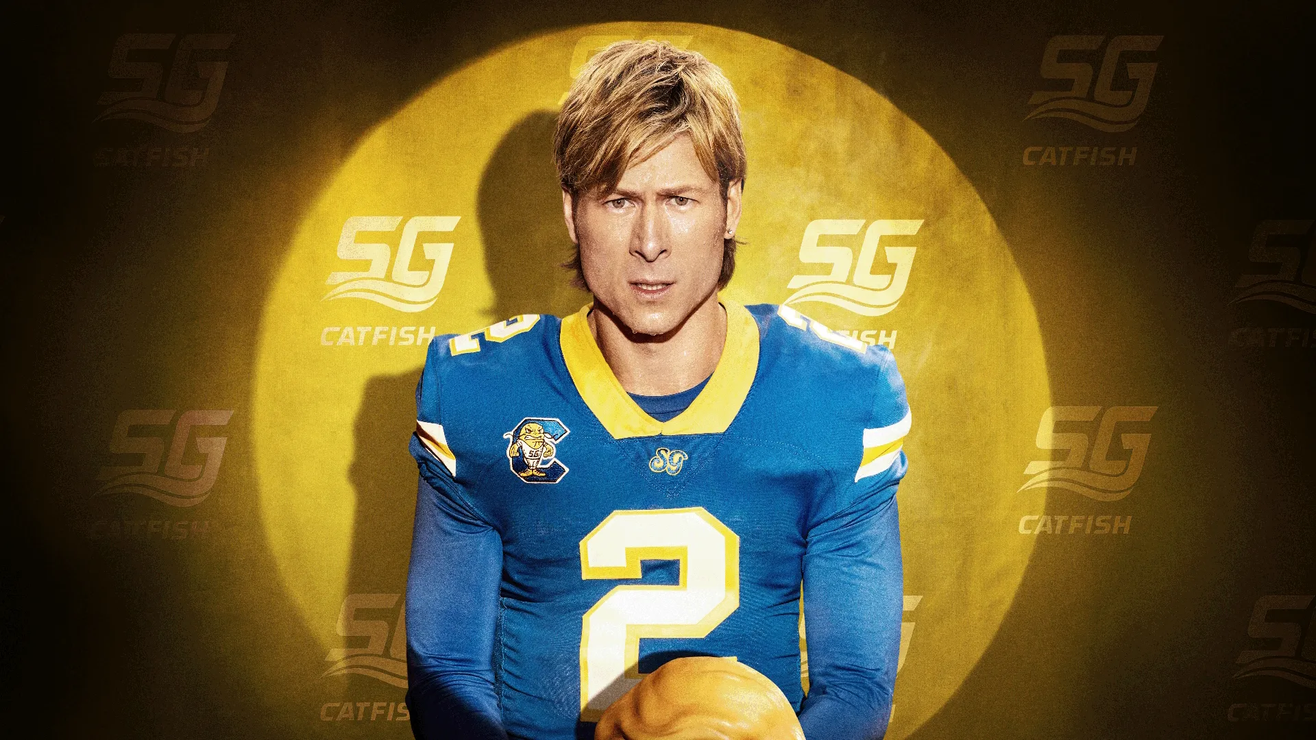 Actor Glen Powell wearing a blonde wig and a blue number 2 "South Georgia Catfish" football jersey in a promotional poster for the Hulu sports comedy series "Chad Powers