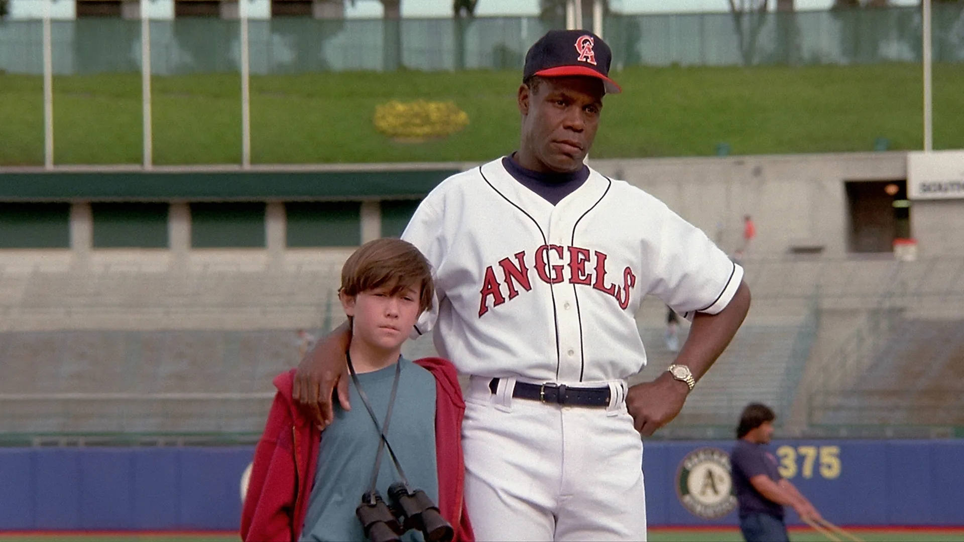 Roger (Joseph Gordon-Levitt) with his coach (Danny Glover) on the baseball field in the 1994 movie Angels in the Outfield.