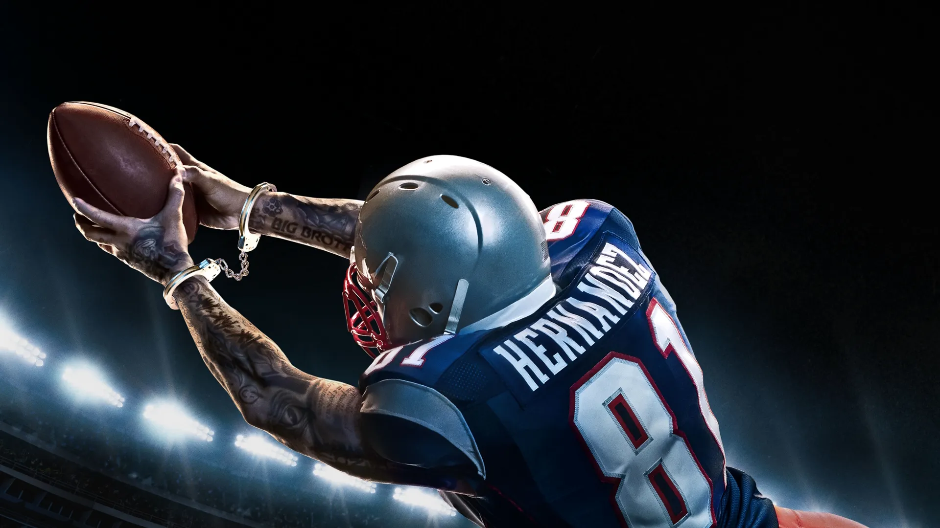 An American football player in a blue and white jersey dives through the air to catch a football during a game.