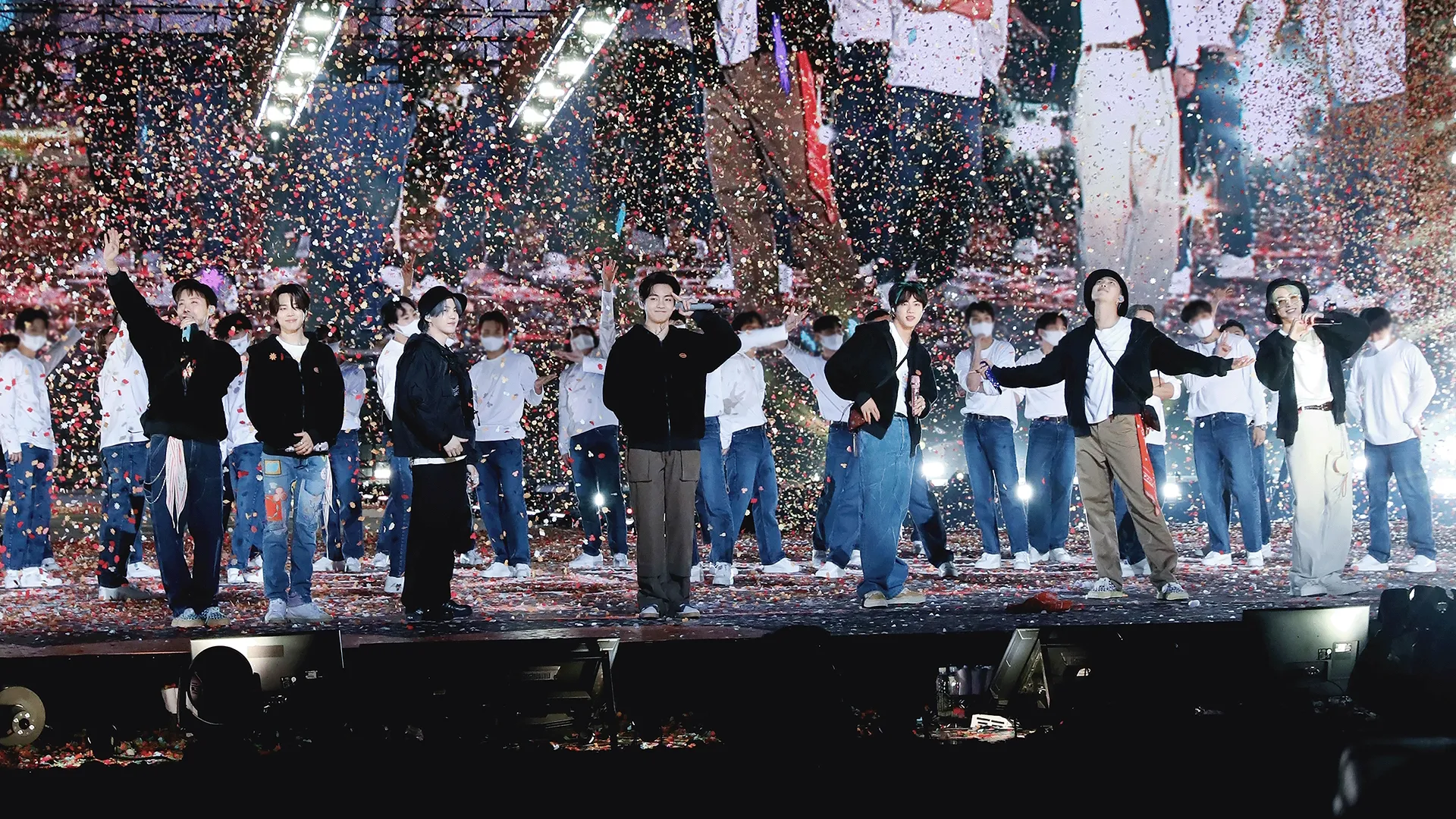 BTS stand together on stage with their dancers as confetti falls