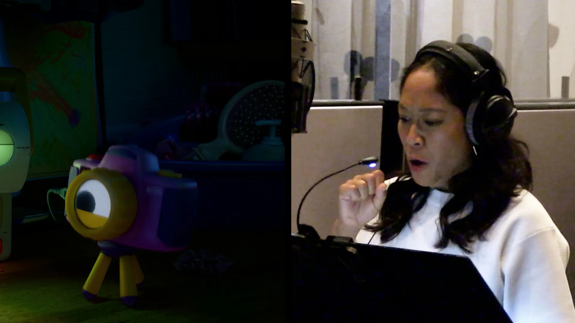 A split screen shows an animated toy camera with one large eye on a tripod on the left, and Shelby Rabara wearing headphones in a recording booth gesturing as she provides its voice on the right.