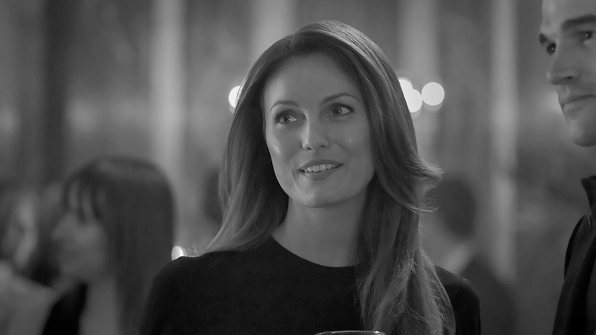 Carloyn Bessette (Sarah Pidgeon) at an event in a black and white set photo from FX's Love Story.