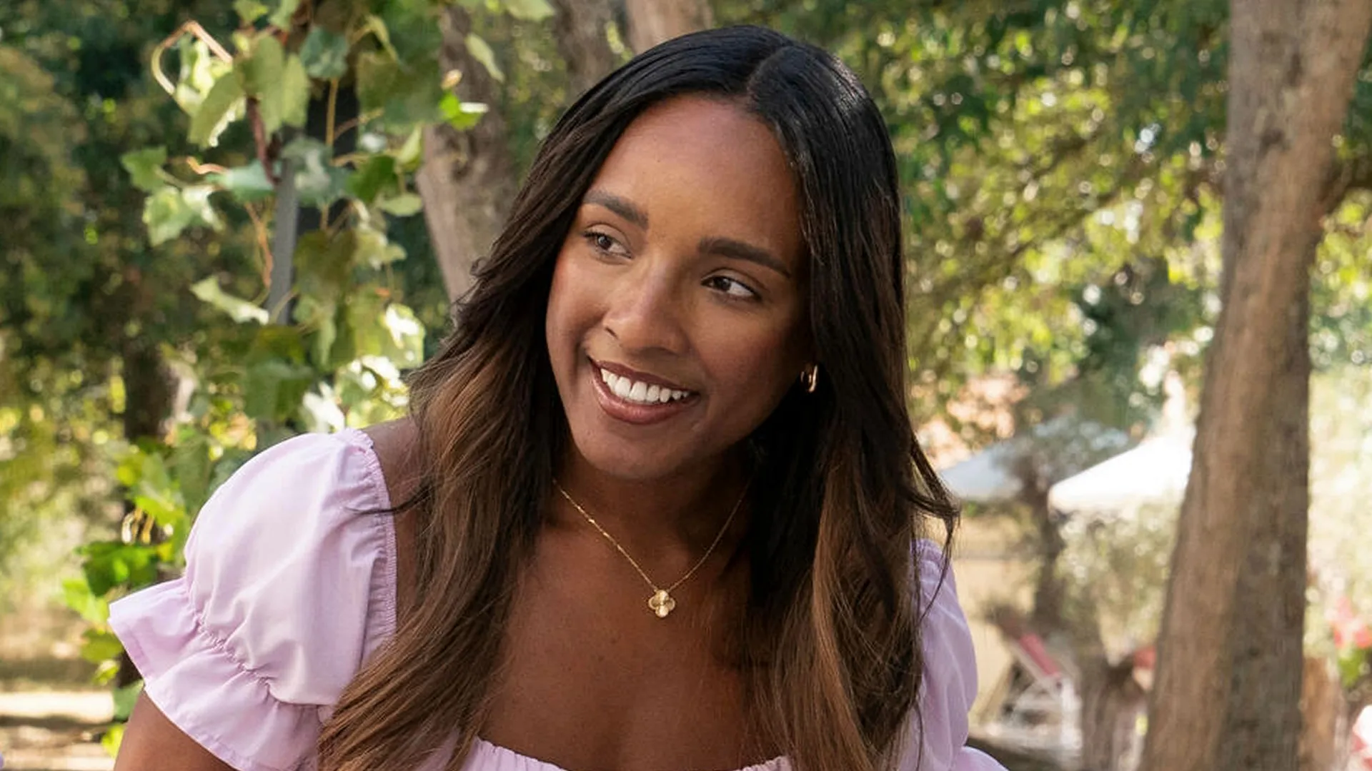 A closeup of Gabriella smiling in front of some trees