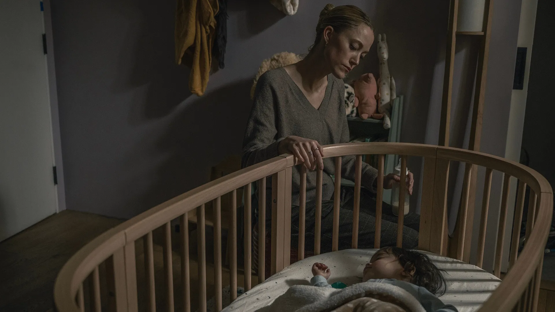 Polly Murphy (Maika Monroe) looks on as a baby sleeps in a cradle.