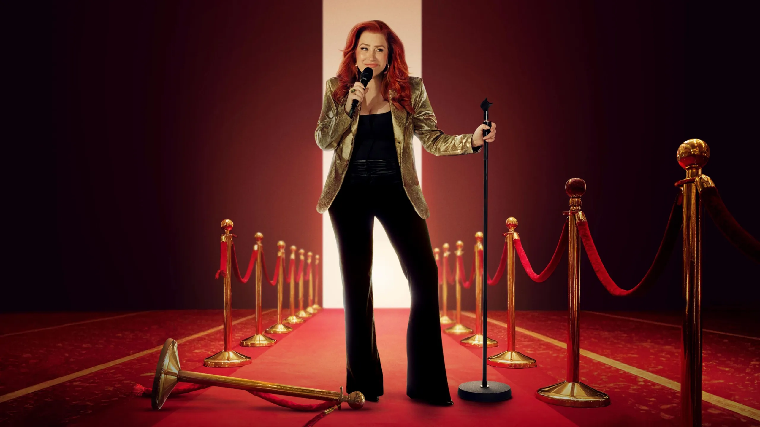 Promotional artwork of Lisa Ann Walter stood on a red carpet holding a microphone, wearing a black outfit with a gold jacket