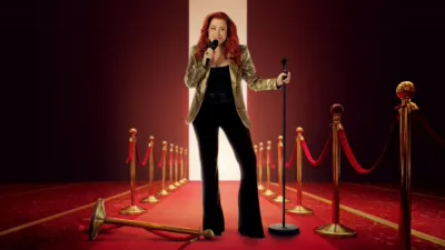 Promotional artwork of Lisa Ann Walter stood on a red carpet holding a microphone, wearing a black outfit with a gold jacket