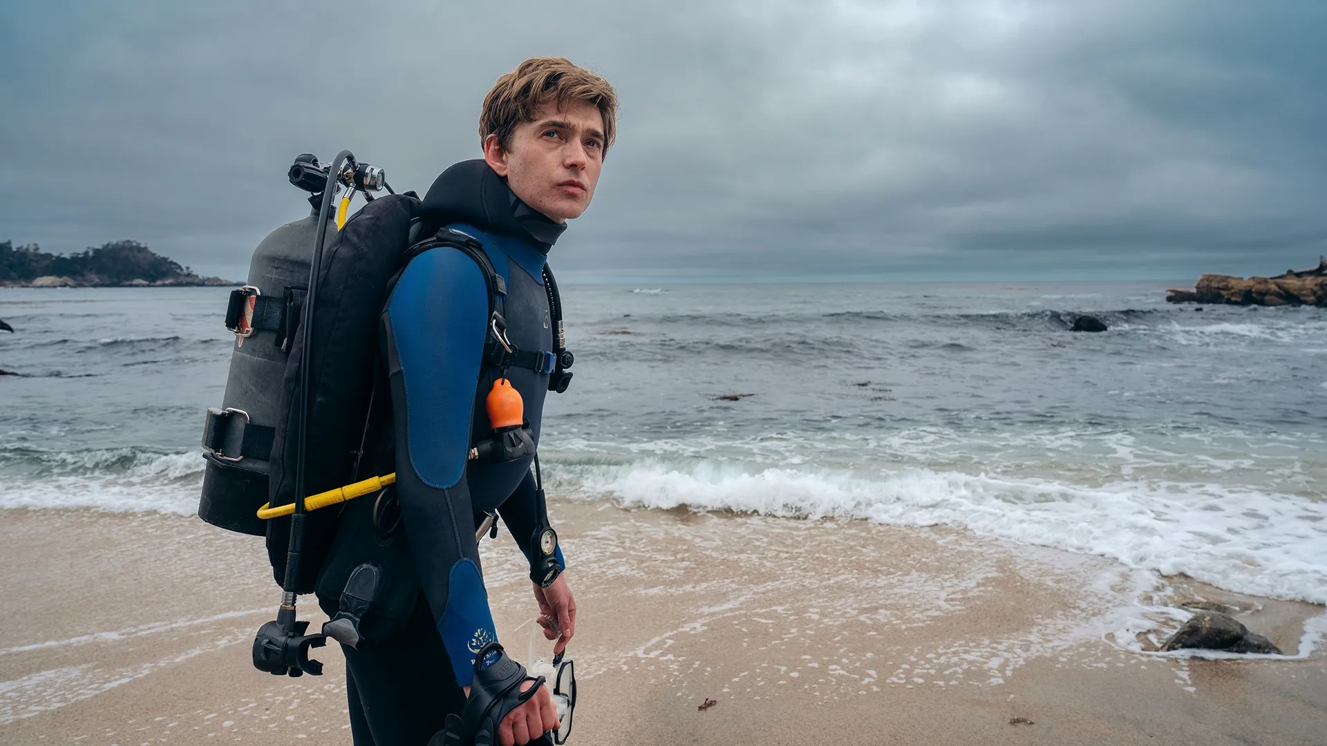 Austin Abrams as Jay Gardiner wearing scuba gear on a beach in Whalefall.