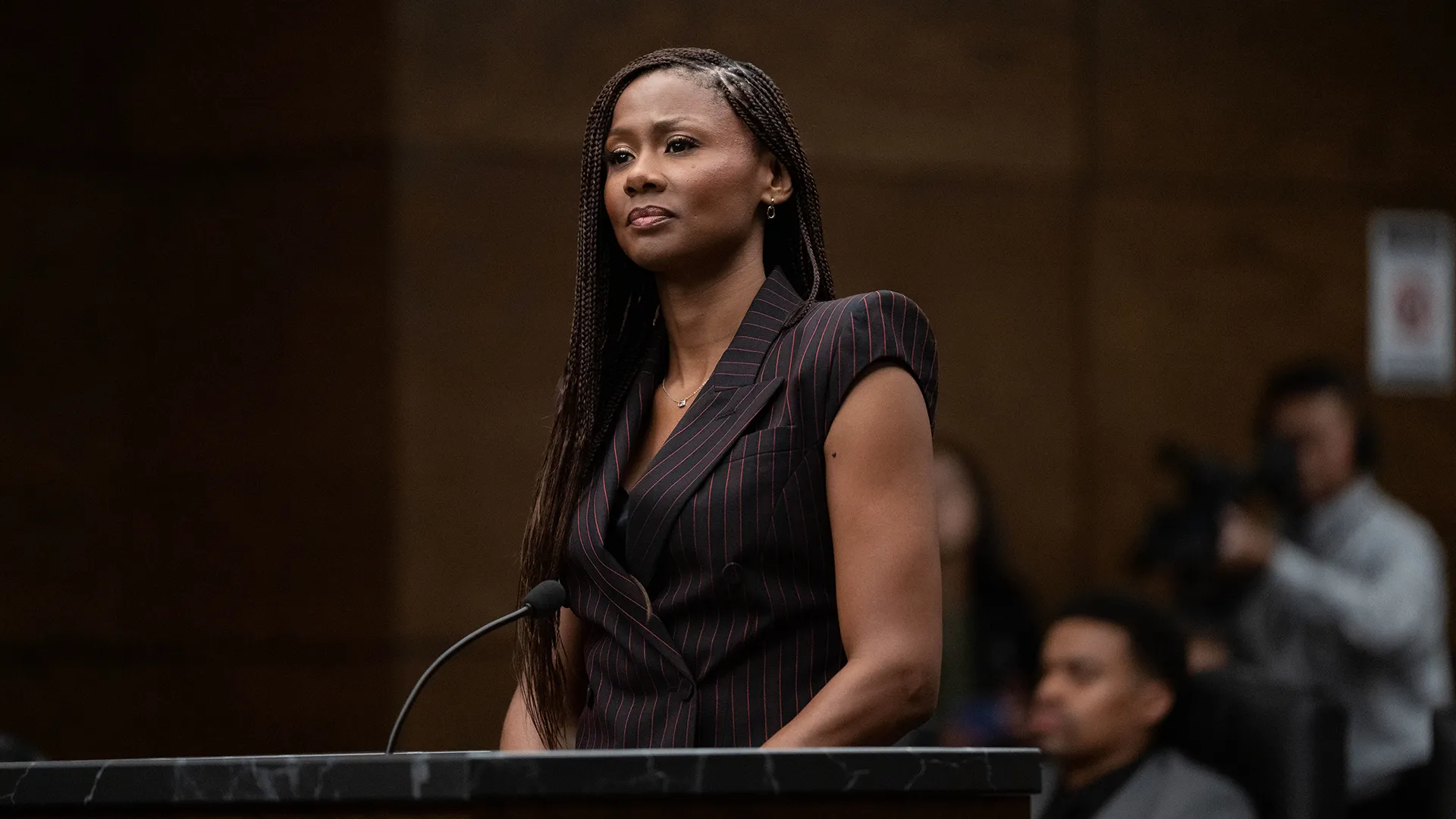 Emayatzy Corinealdi as Jax Stewart wearing a striking burgundy pantsuit n a courtroom