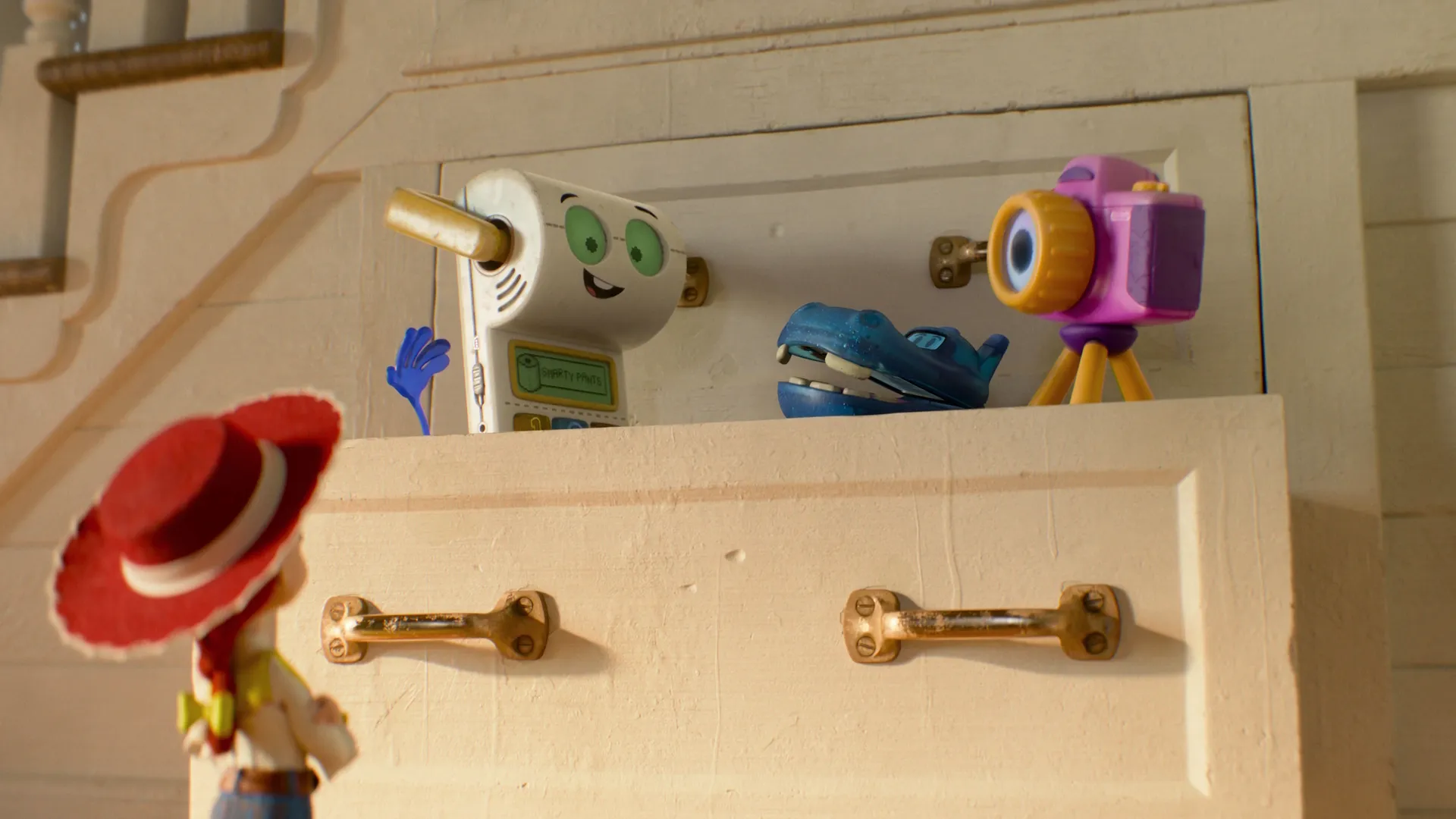 Jessie the cowgirl looking up at three new tech toy characters—Smarty Pants the white toilet-training device, Atlas the blue GPS hippo, and Snappy the purple toy camera—standing on top of a dresser from Disney and Pixar's Toy Story 5