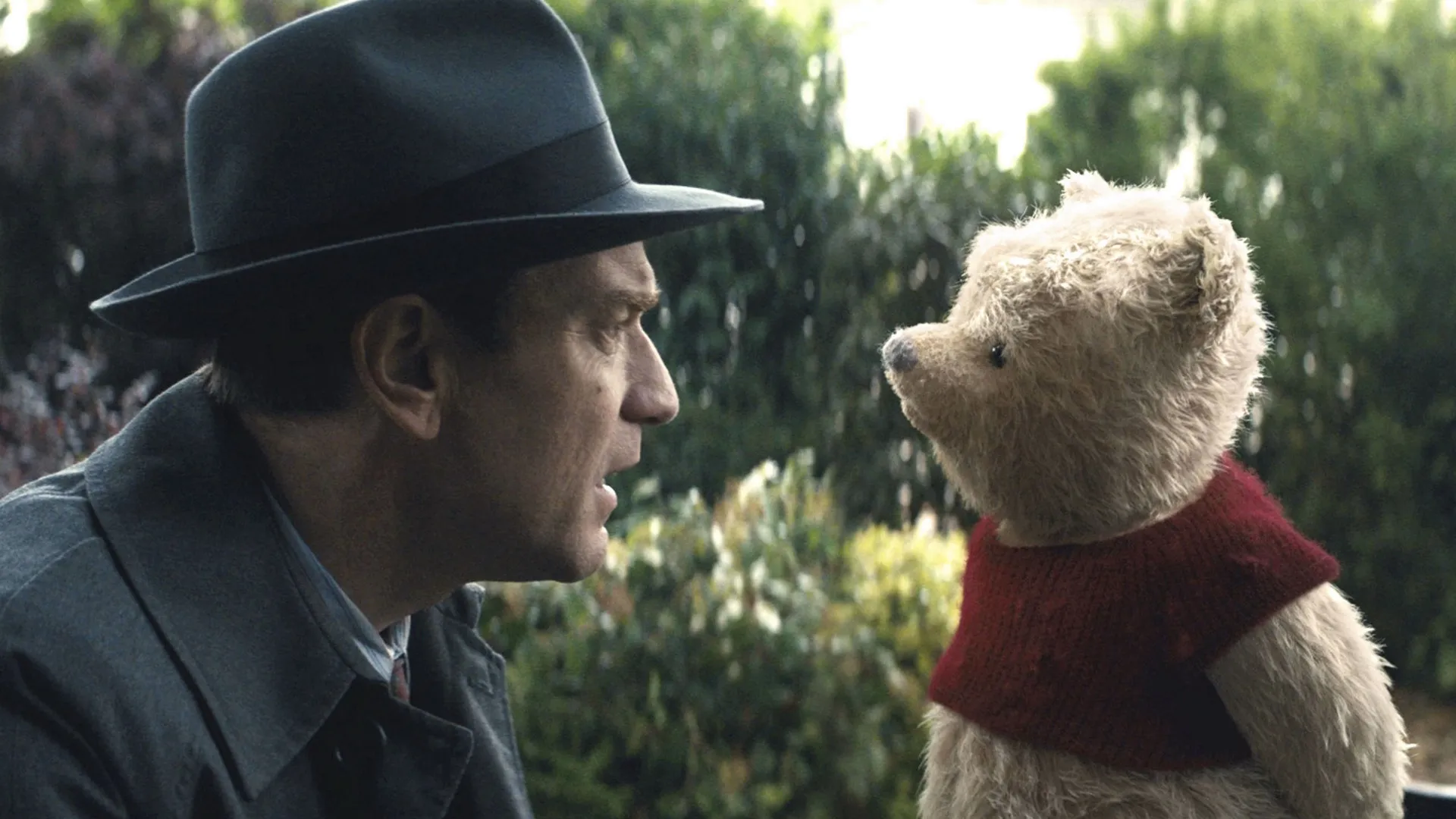 An older Christopher Robin (Ewan McGregor) talks to Winnie the Pooh.