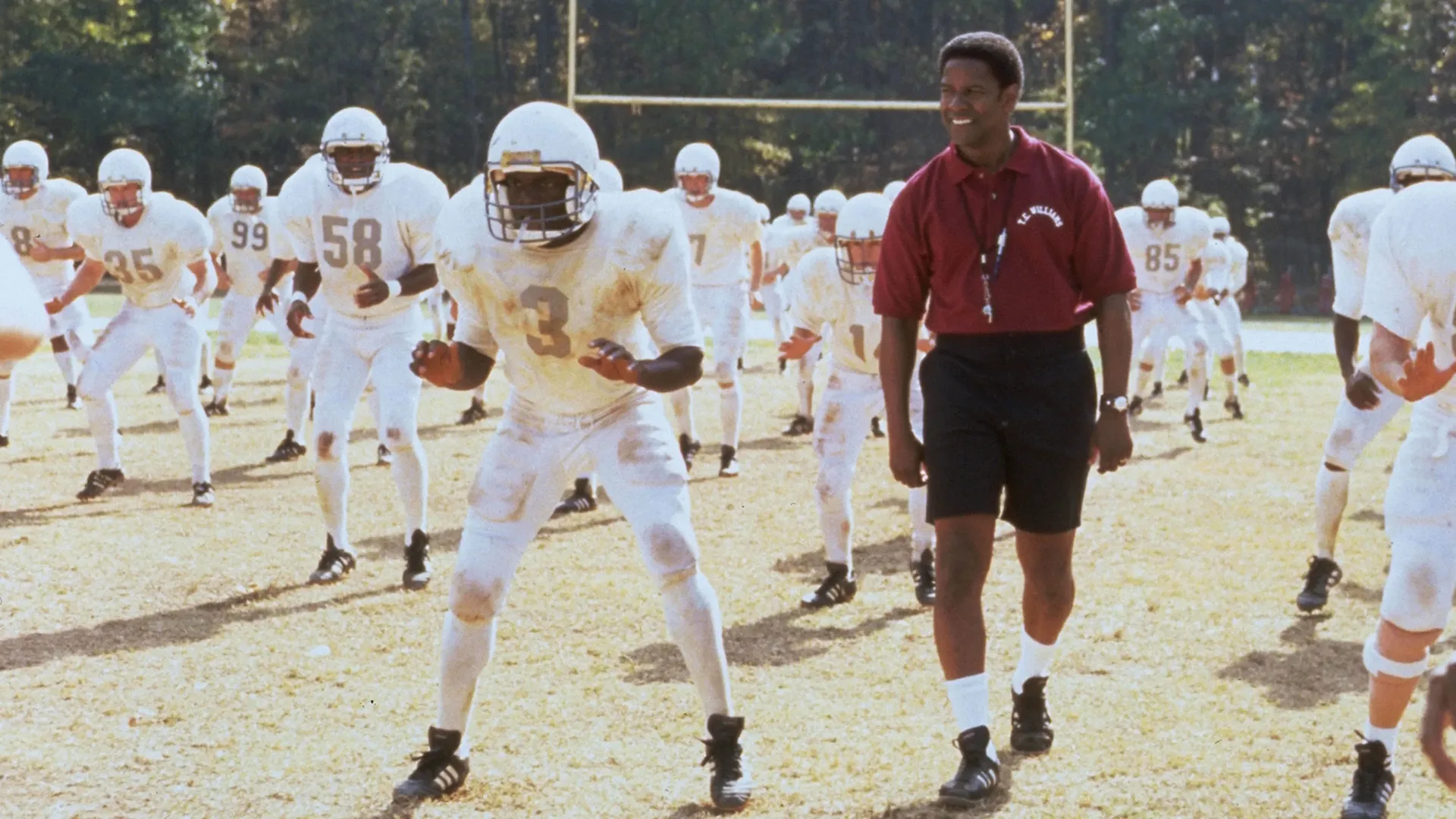 Coach Herman Boone (played by Denzel Washington) surveys the Titans as they train on the field.