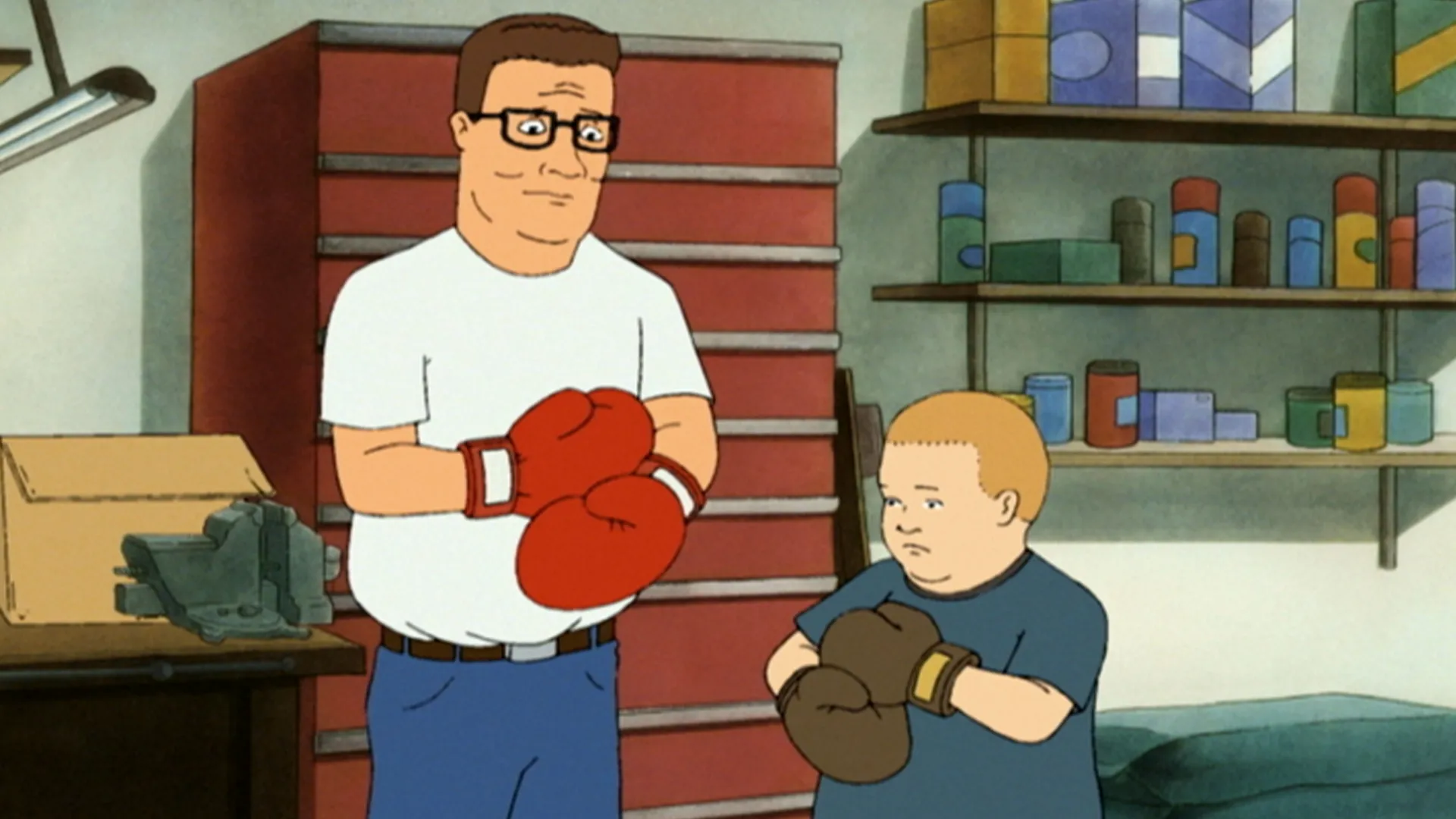Hank (Mike Judge) and Bobby (Pamela Adlon) stand in the garage wearing boxing gloves.