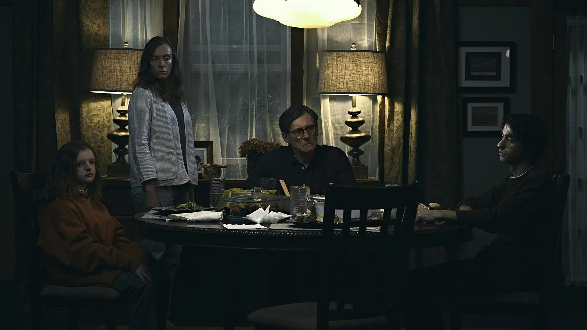 A family sits at a dimly lit dining table.