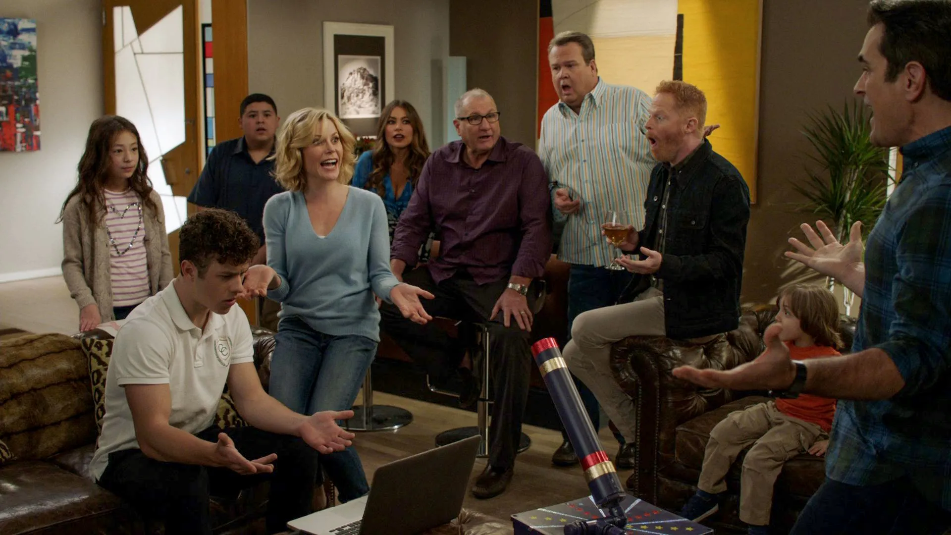 The extended family from Modern Family gathers in a living room.