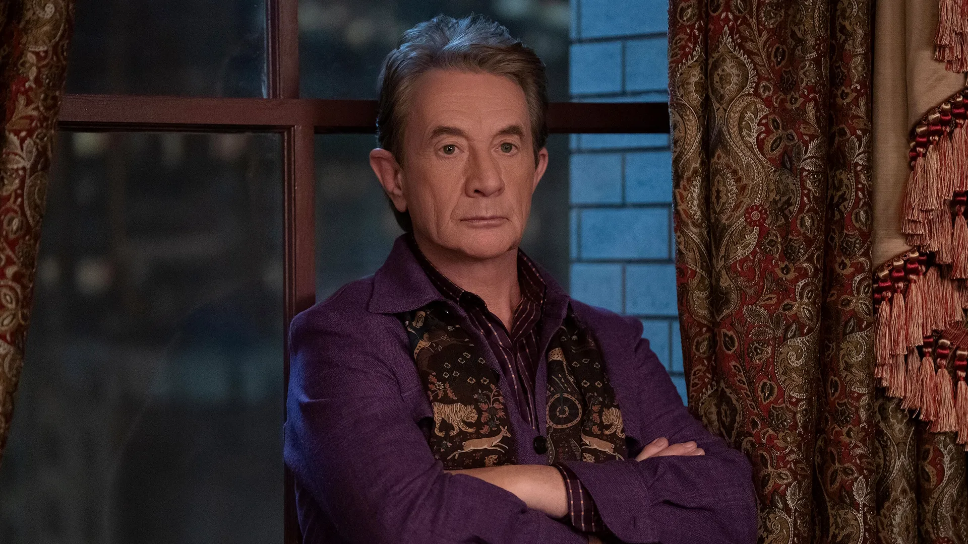 Emmy® nominee Martin Short (as Oliver Putnam) stands with his arms folded in Only Murders in the Building.
