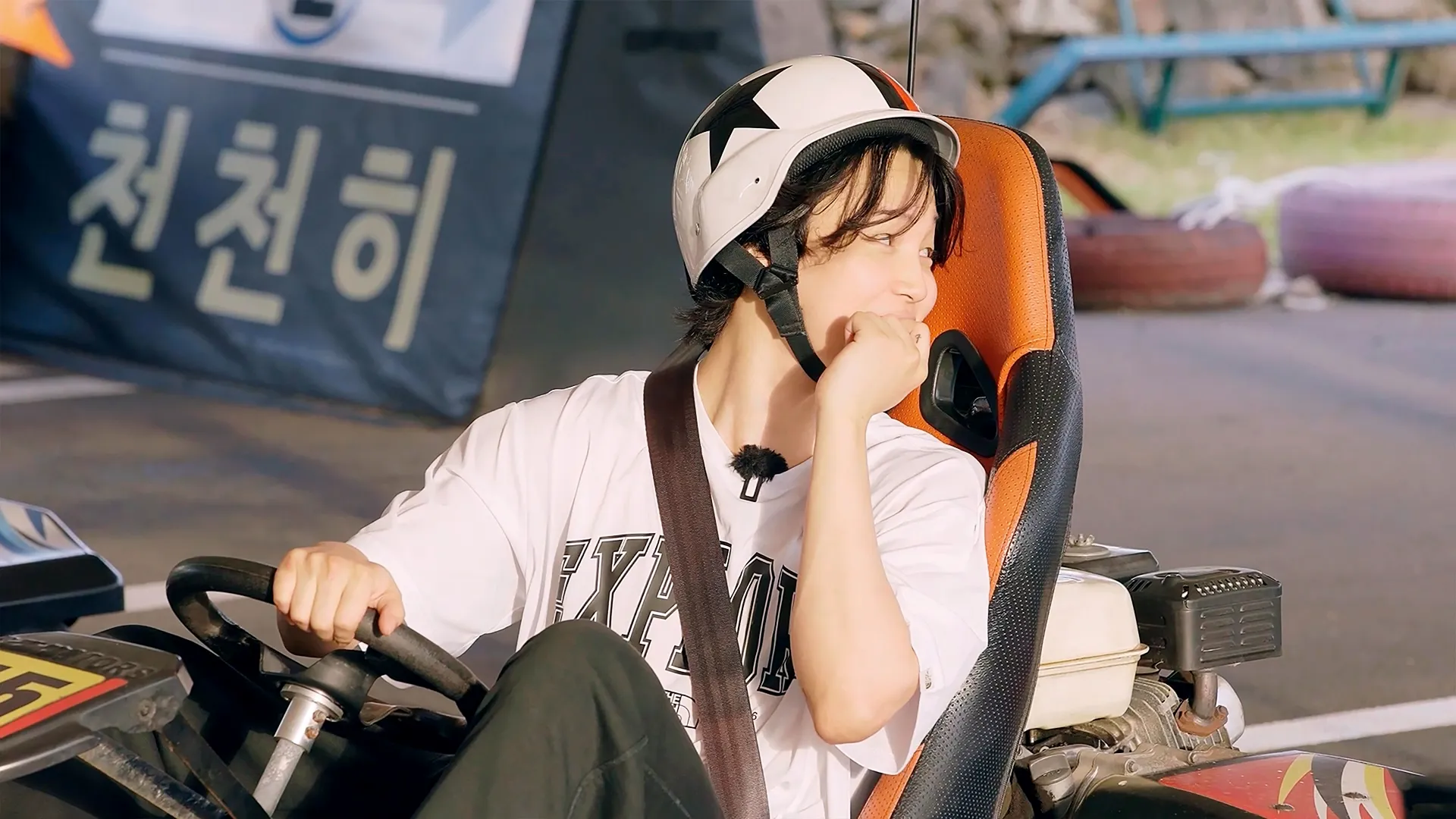 Jimin (of BTS) rides in a go-kart.