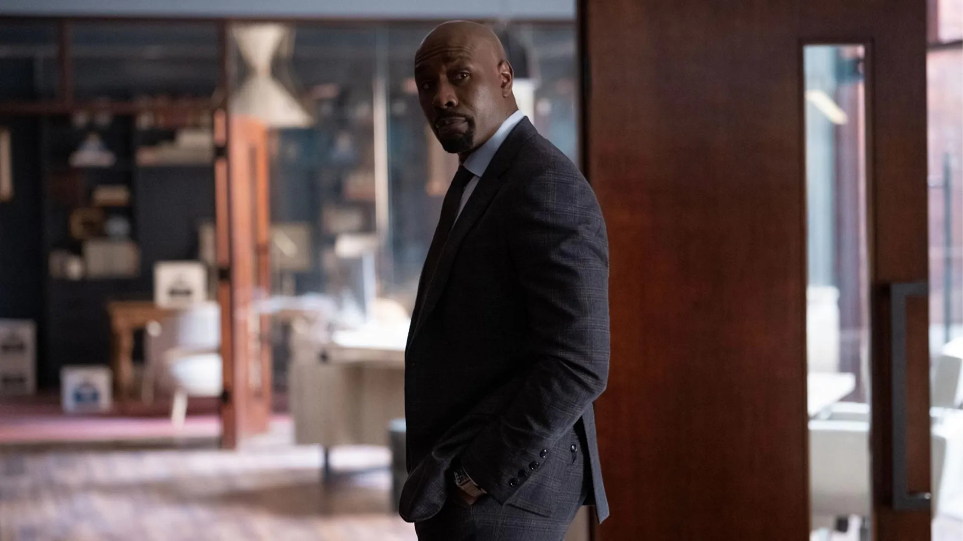  Morris Chestnut as defense attorney Corey Cash, dressed in a suit, standing in an office
