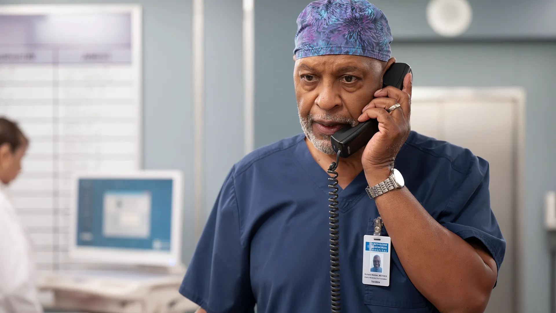 Dr. Richard Webber (James Pickens Jr.) answers the phone in his scrubs.